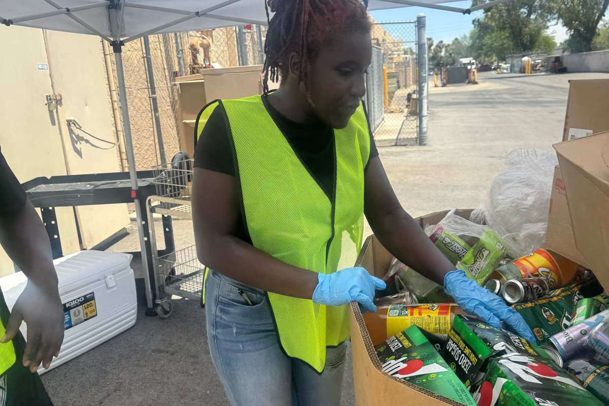 A volunteer in gloves packing canned goods into a box.