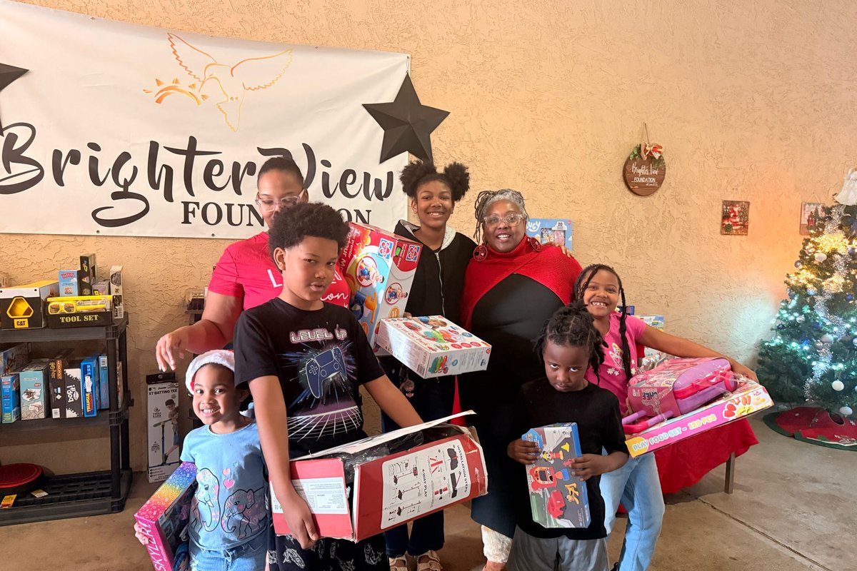 Families holding wrapped gifts at a holiday giveaway under the Brighter View banner.