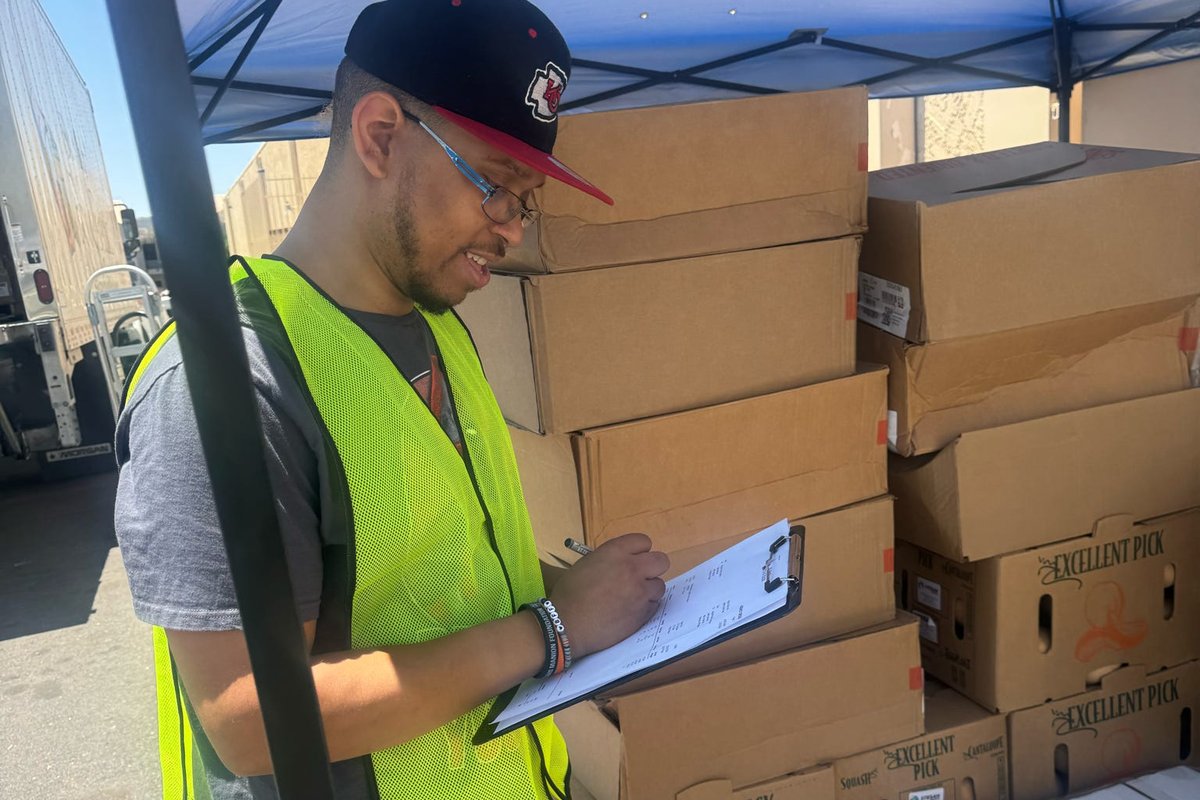 A participant in a safety vest checking inventory on a clipboard.