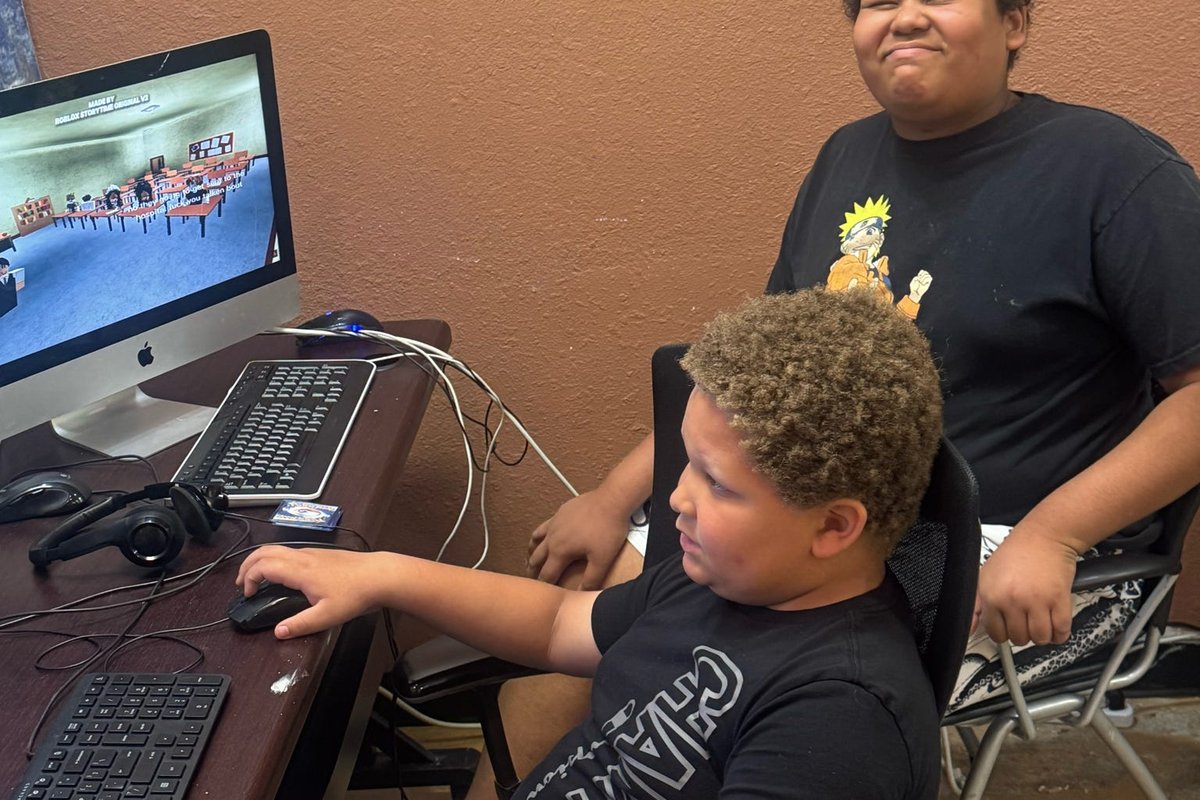 A trainee working at a computer with a classmate nearby.