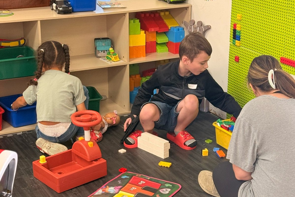 Children and adults playing with blocks and toys in the youth room.