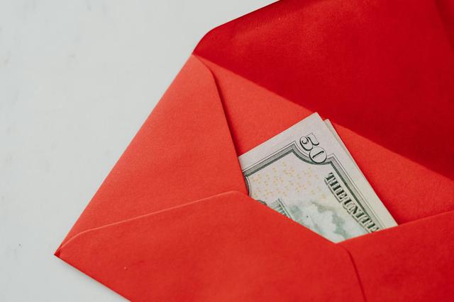 Close-up of fifty dollar bill in a vibrant red envelope, ideal for gift or money exchange stock photo.