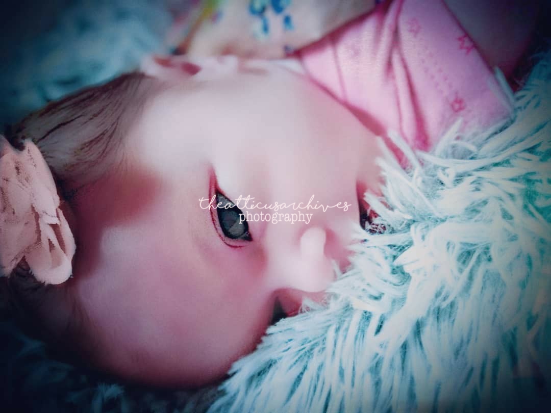 A sleeping infant wrapped in soft blankets, warm gentle light, peaceful quiet moment