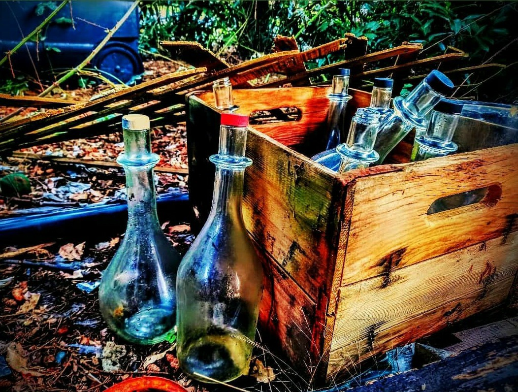 Glass bottles arranged in a vintage wooden crate, found-object still life, textured composition