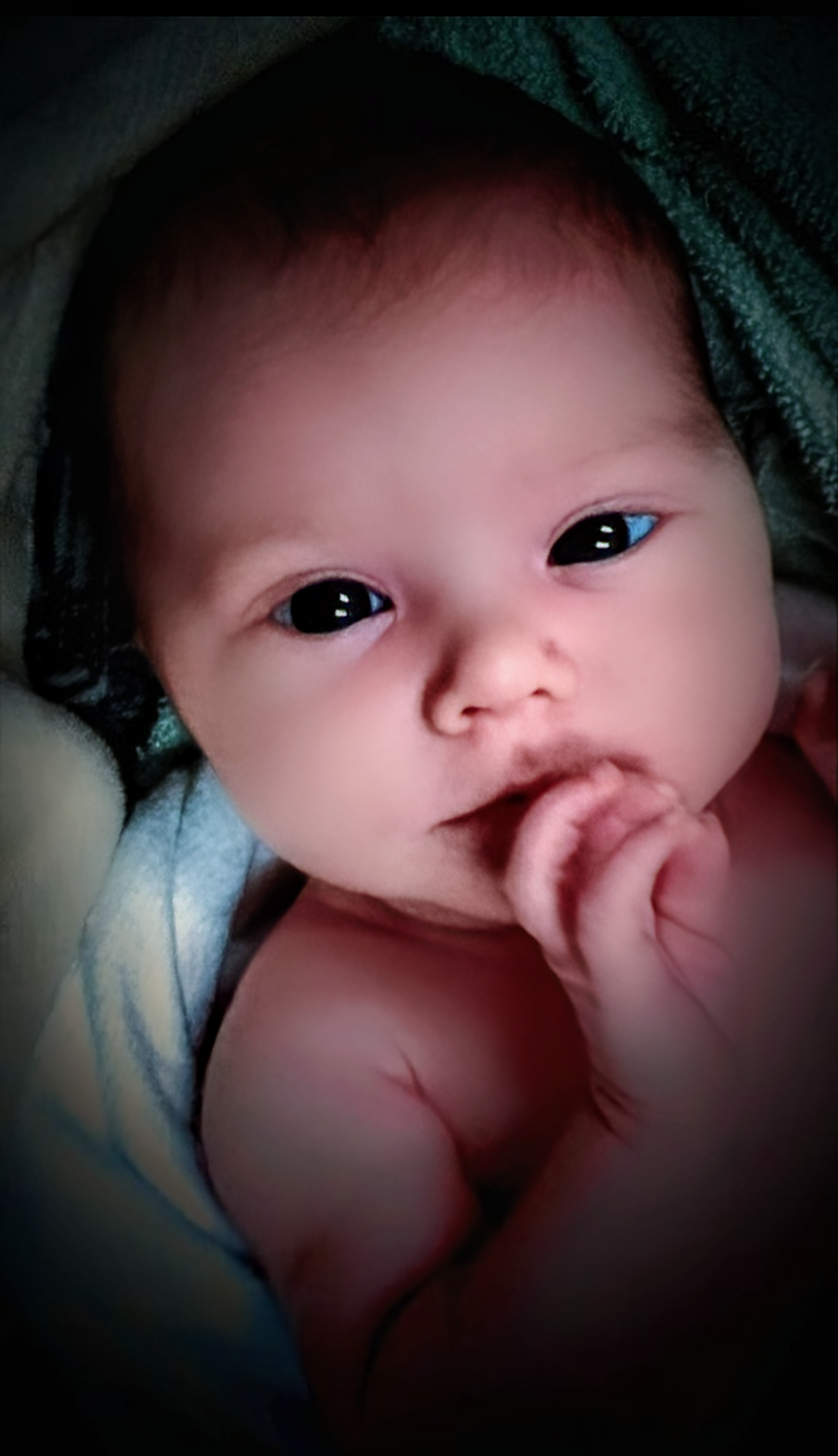 An intimate newborn portrait with soft wrapping or blankets, tender family moment