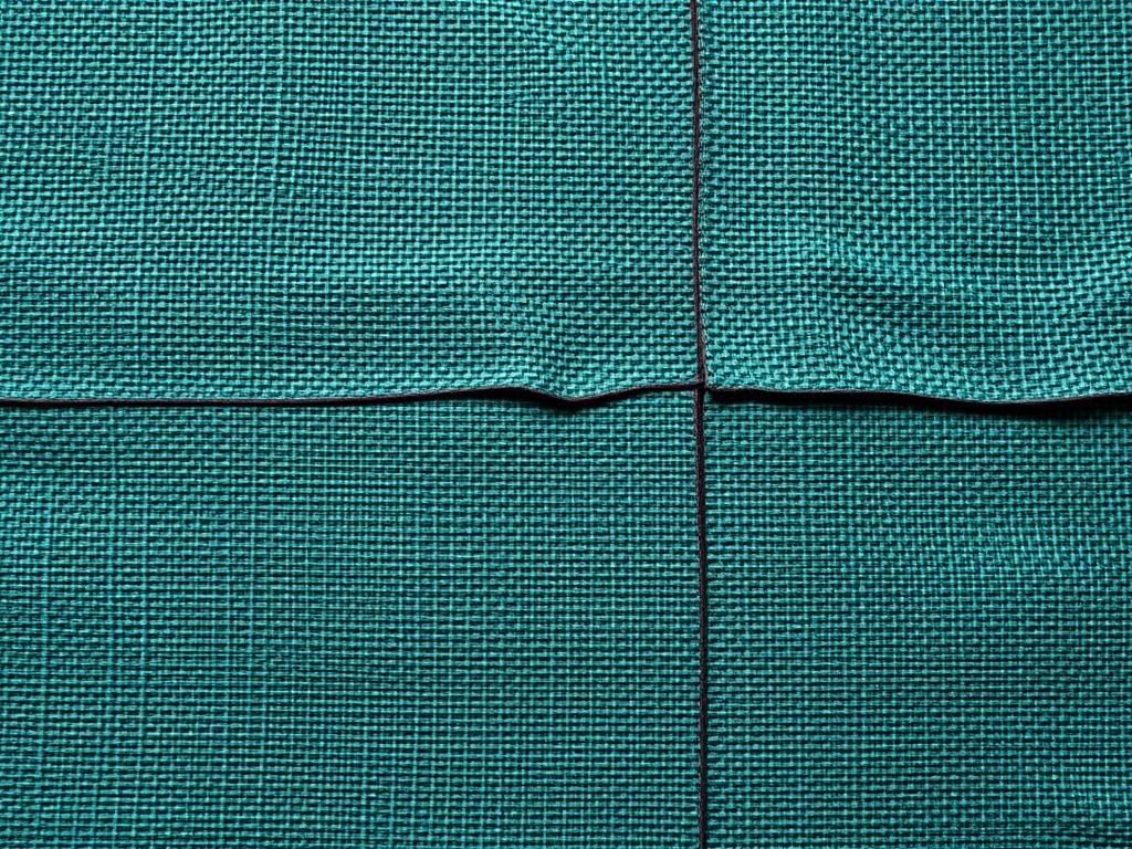 A highly detailed close-up shot of a Colombian reinforced tarp (lona reforzada) showcasing its texture and durability. The tarp should be prominently displayed against a simple background, emphasizing its quality and robustness. The focus should be sharp, highlighting the fabric's weave and strength, captured using a 45mm f/1.2 lens style, with a color palette that complements the RGB(50, 170, 39) primary color.