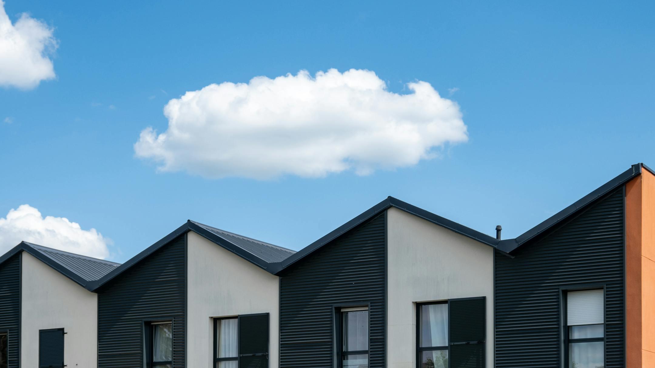 Modern building facade with textured walls and unique roof design beneath a clear blue sky.