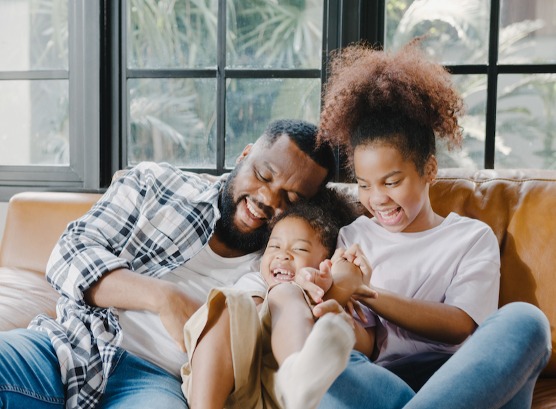 happy-cheerful-african-american-family-dad-daughter-having-fun-cuddle-play-sofa-while-birthday-house-1674828654915.jpg