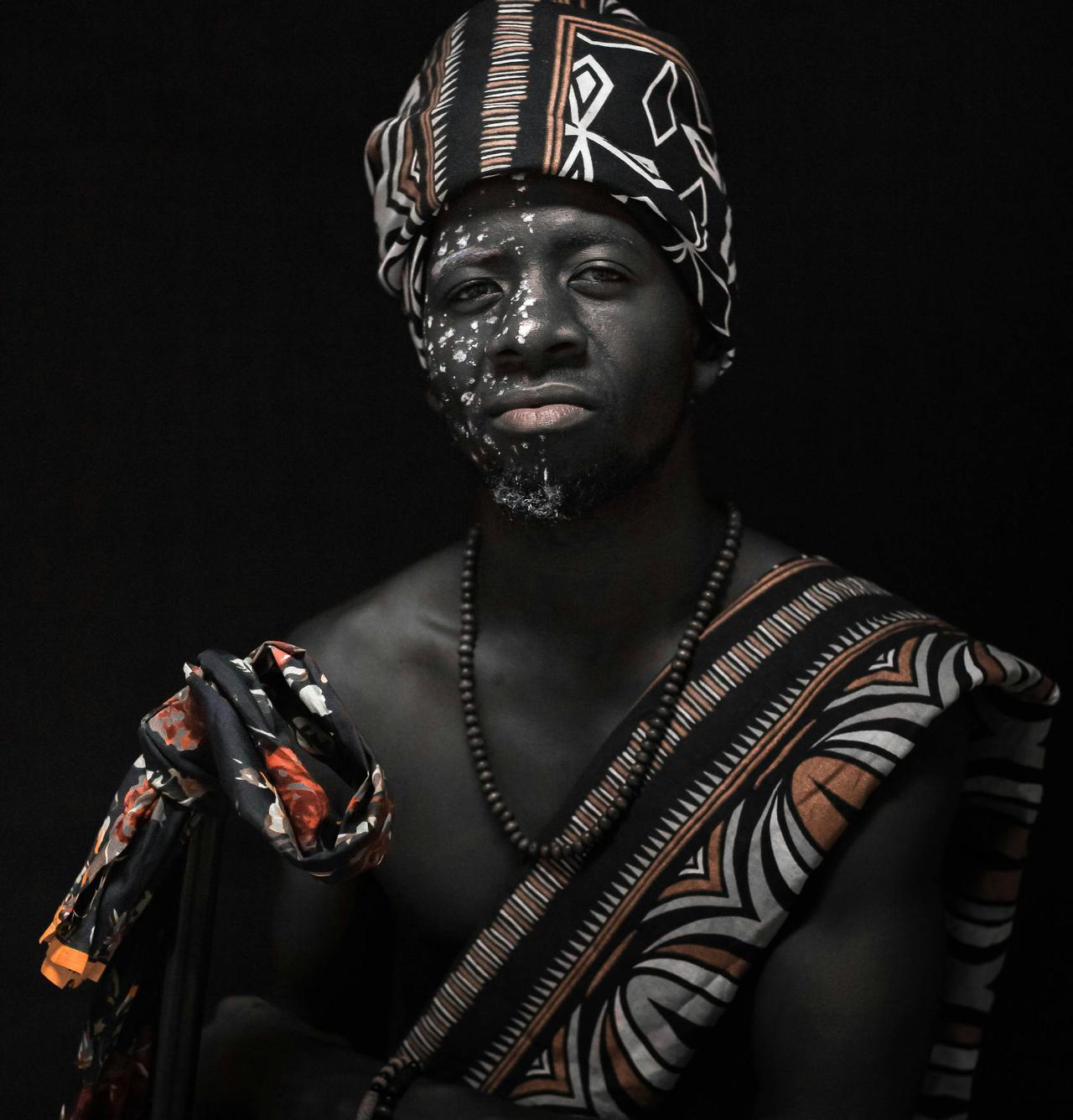 Studio portrait of an African man wearing traditional Angolan tribal attire with face paint.