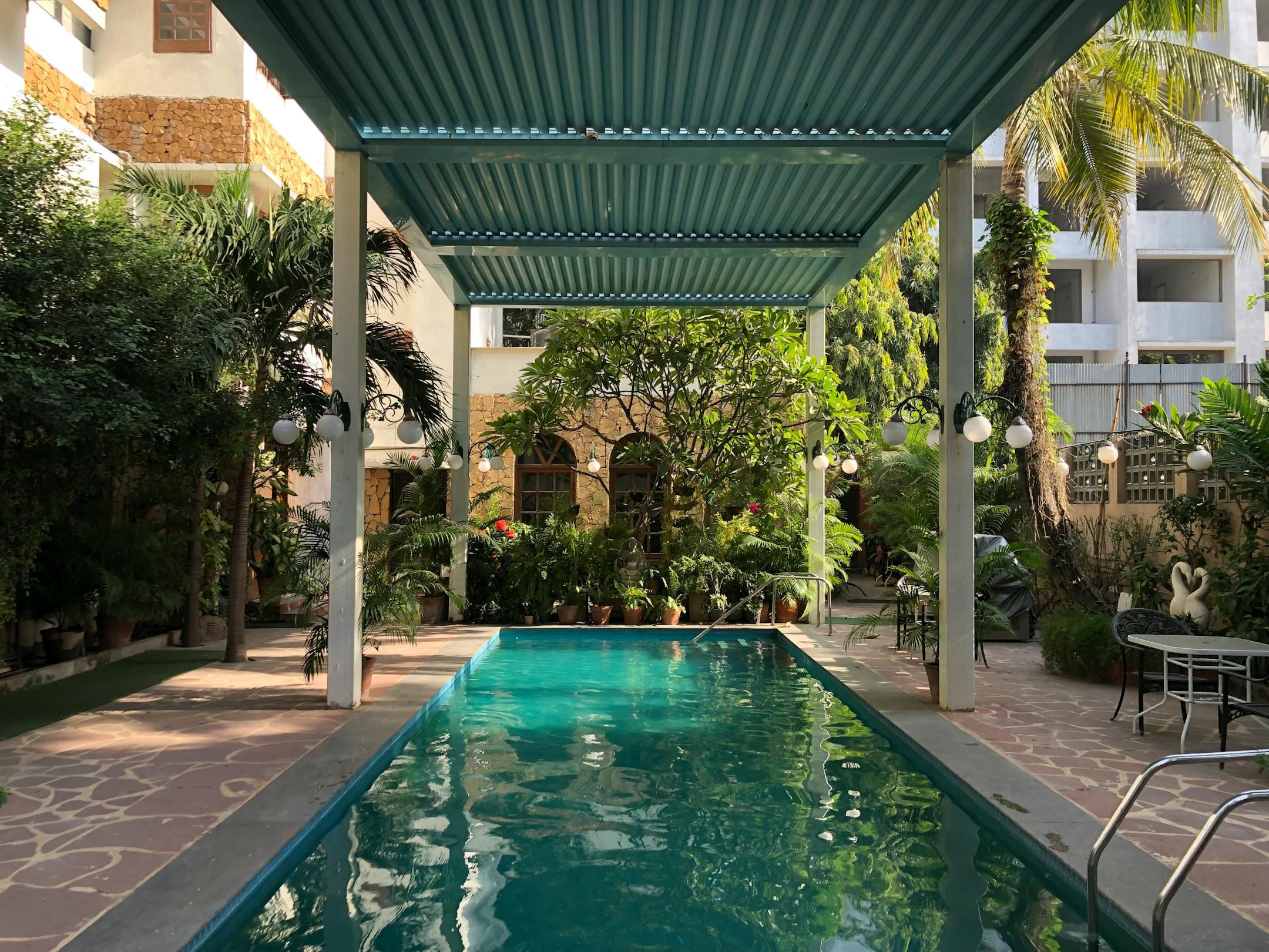 Serene tropical outdoor pool surrounded by lush greenery and shaded canopy.