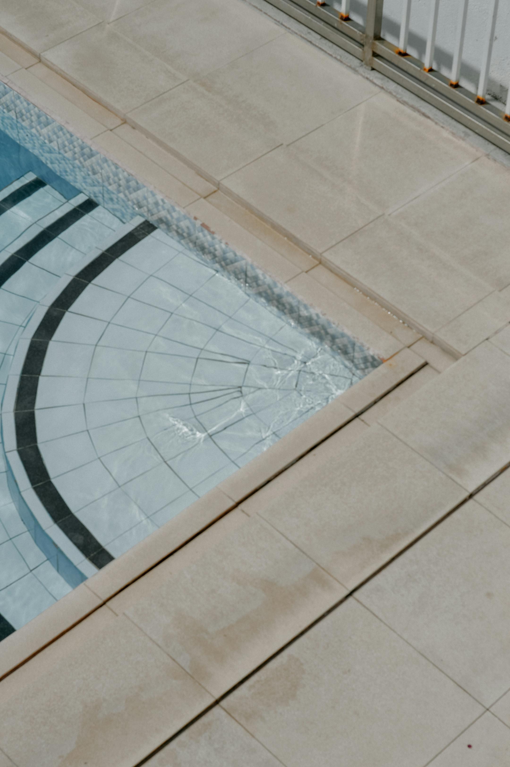 Elegant geometric pool with a detailed tiled deck, showcasing architectural beauty and tranquility.