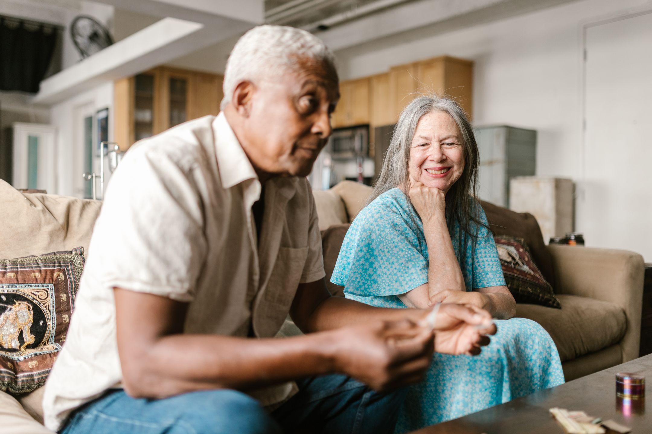An interracial elderly couple enjoying a relaxed moment together indoors, smiling and happy.