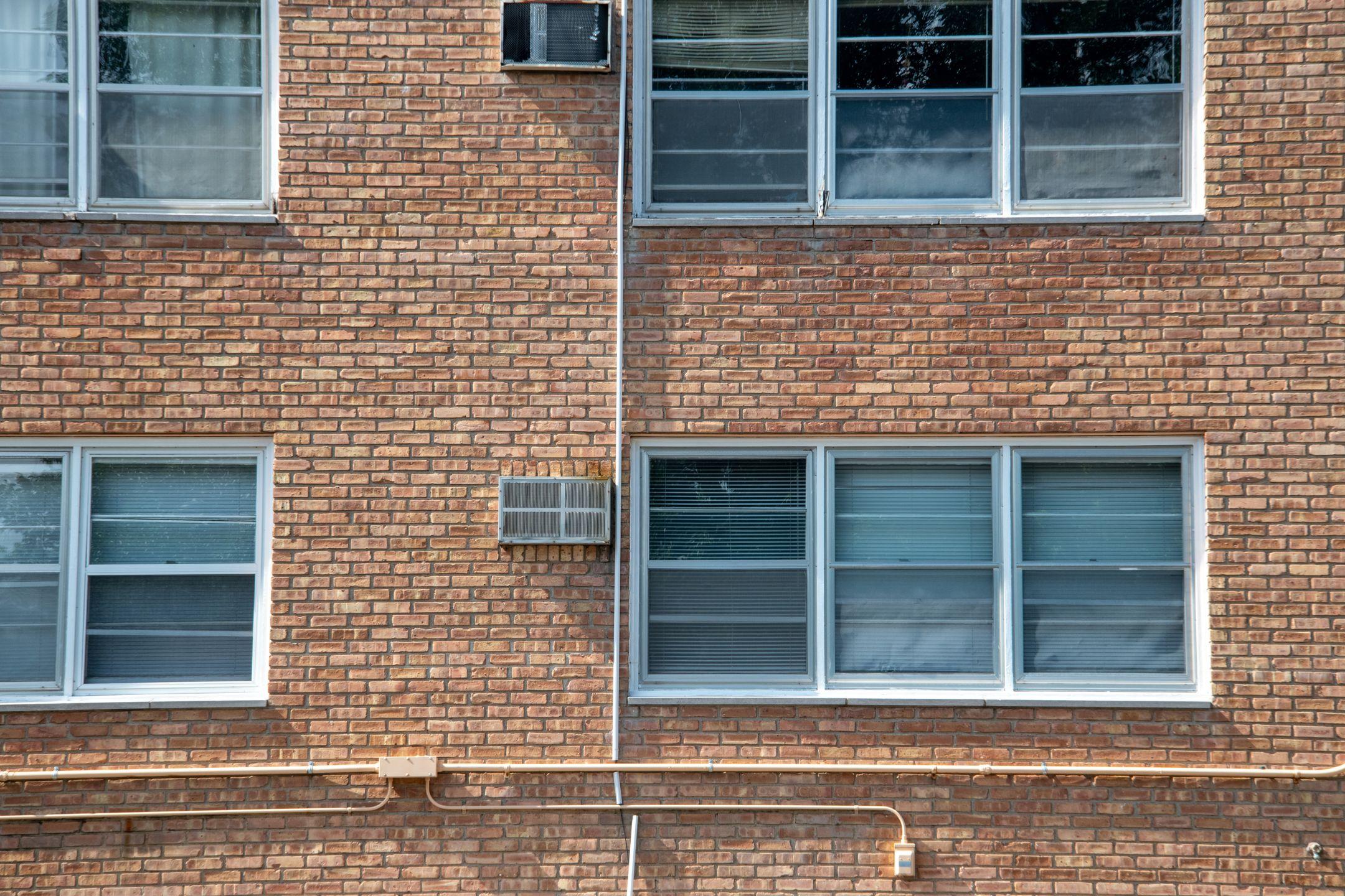 Close-up of a brick apartment facade featuring multiple modern aluminum windows.