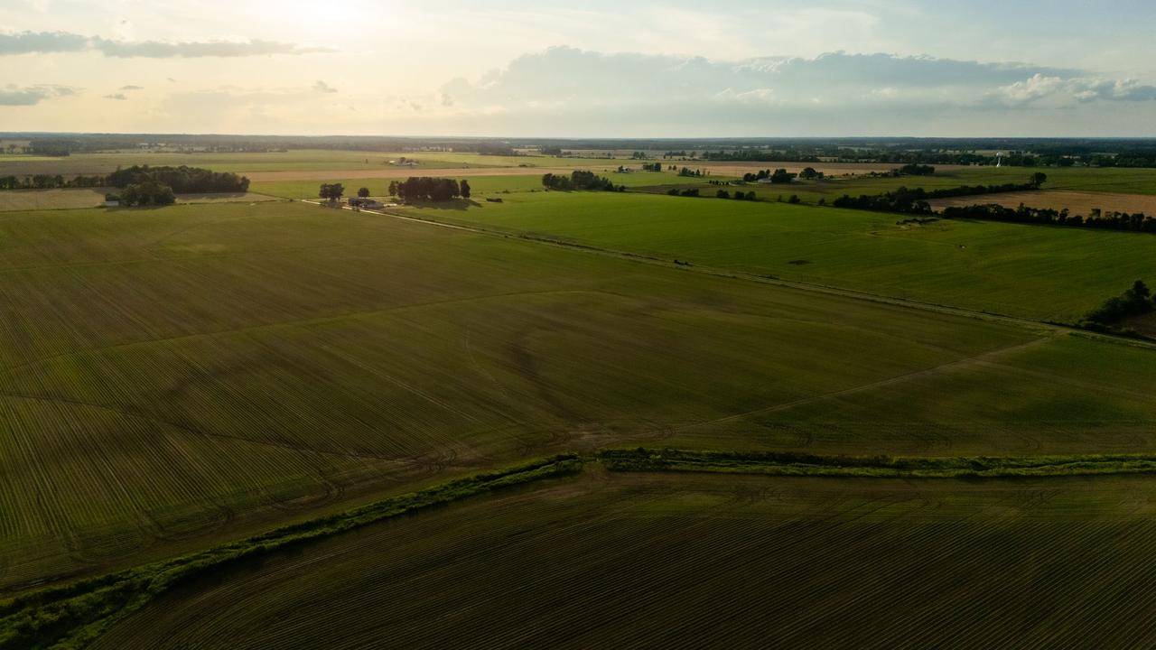 Aerial view of vast crop fields at sunset, showcasing serene farmland and agricultural landscape.