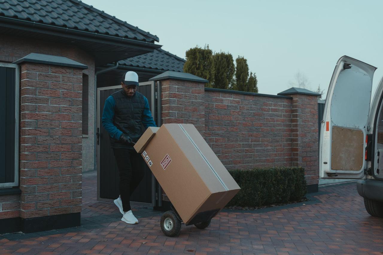 Person carrying moving boxes to a house