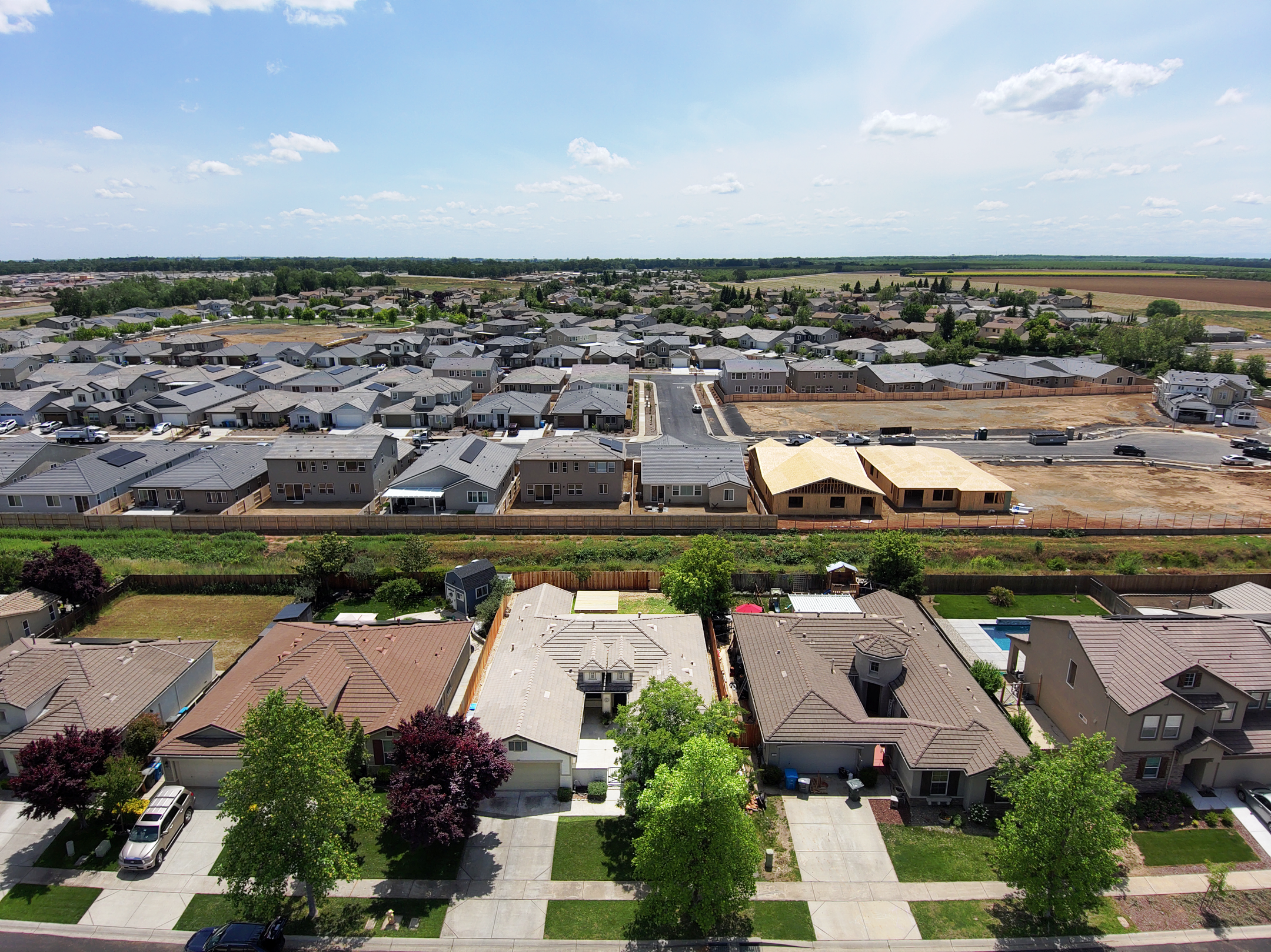 Drone view of suburban neighborhood with new housing developments and green surroundings.