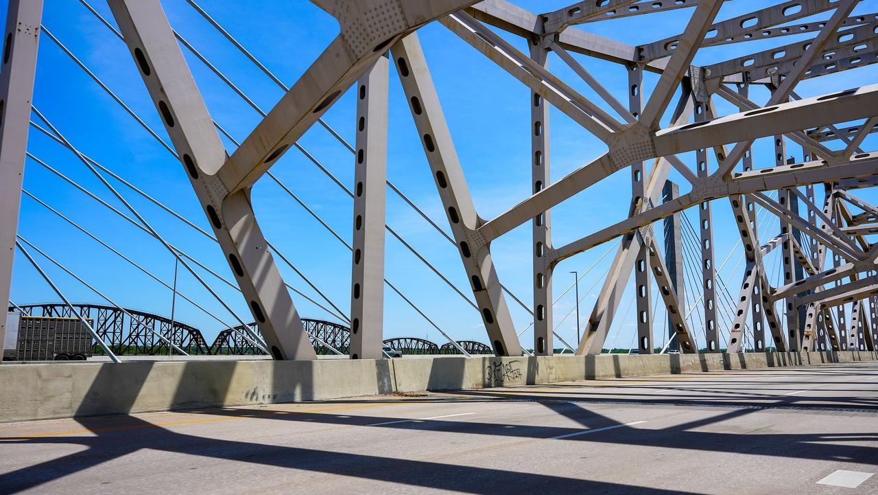 View of a steel bridge structure with shadows and blue sky in Louisville, Kentucky.