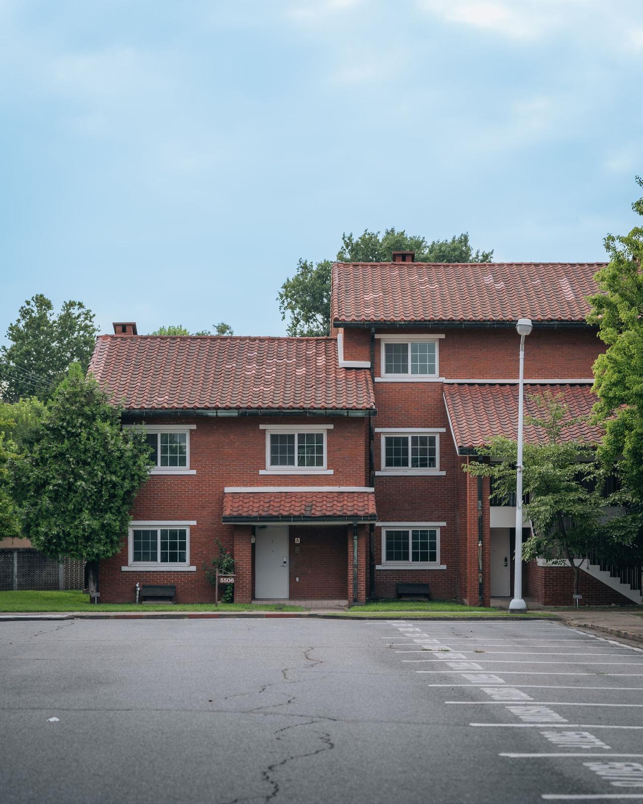 Red brick building on a quiet street with trees and ample parking.