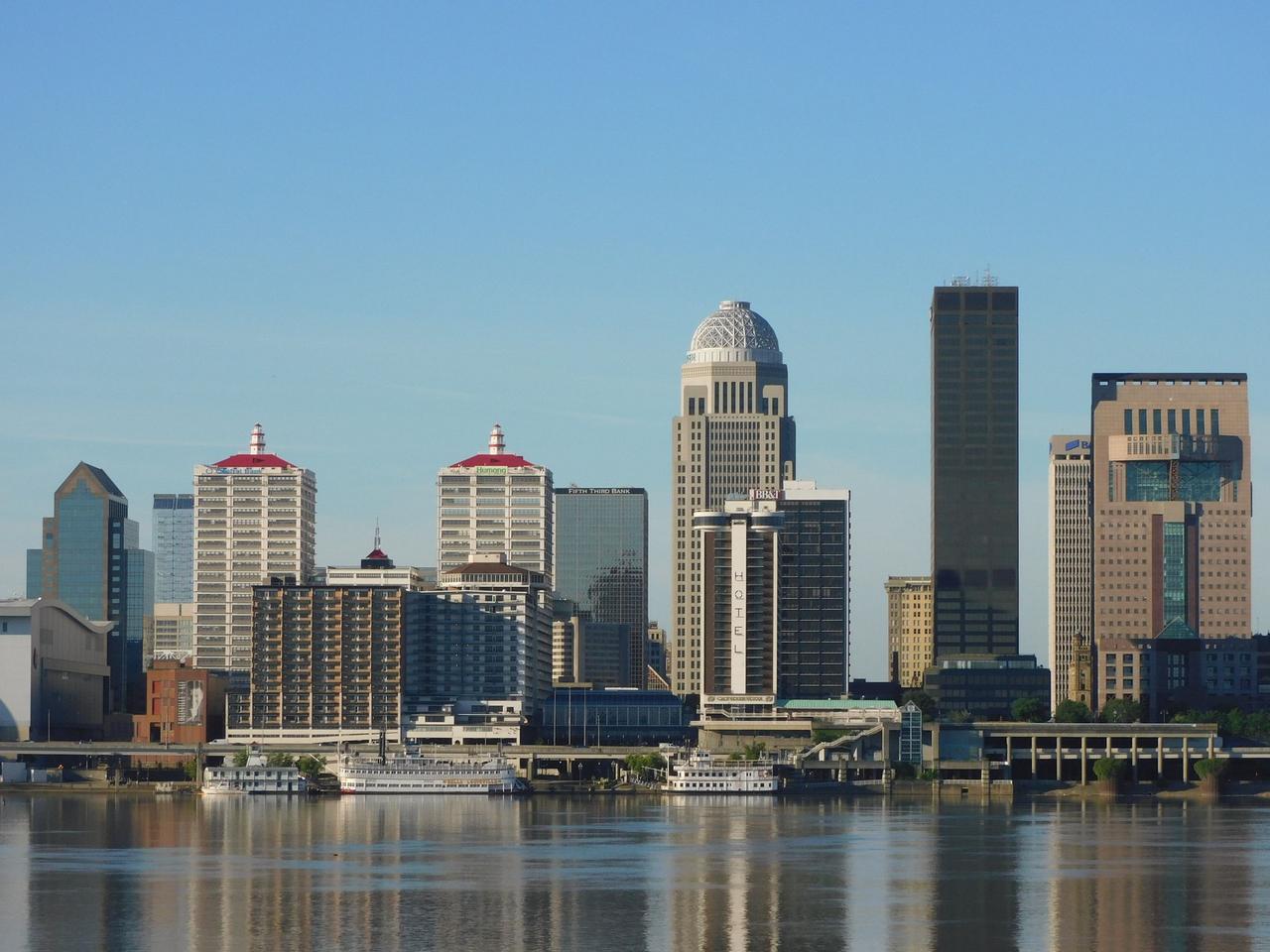 Stunning view of Louisville's skyline with modern skyscrapers reflecting on river.