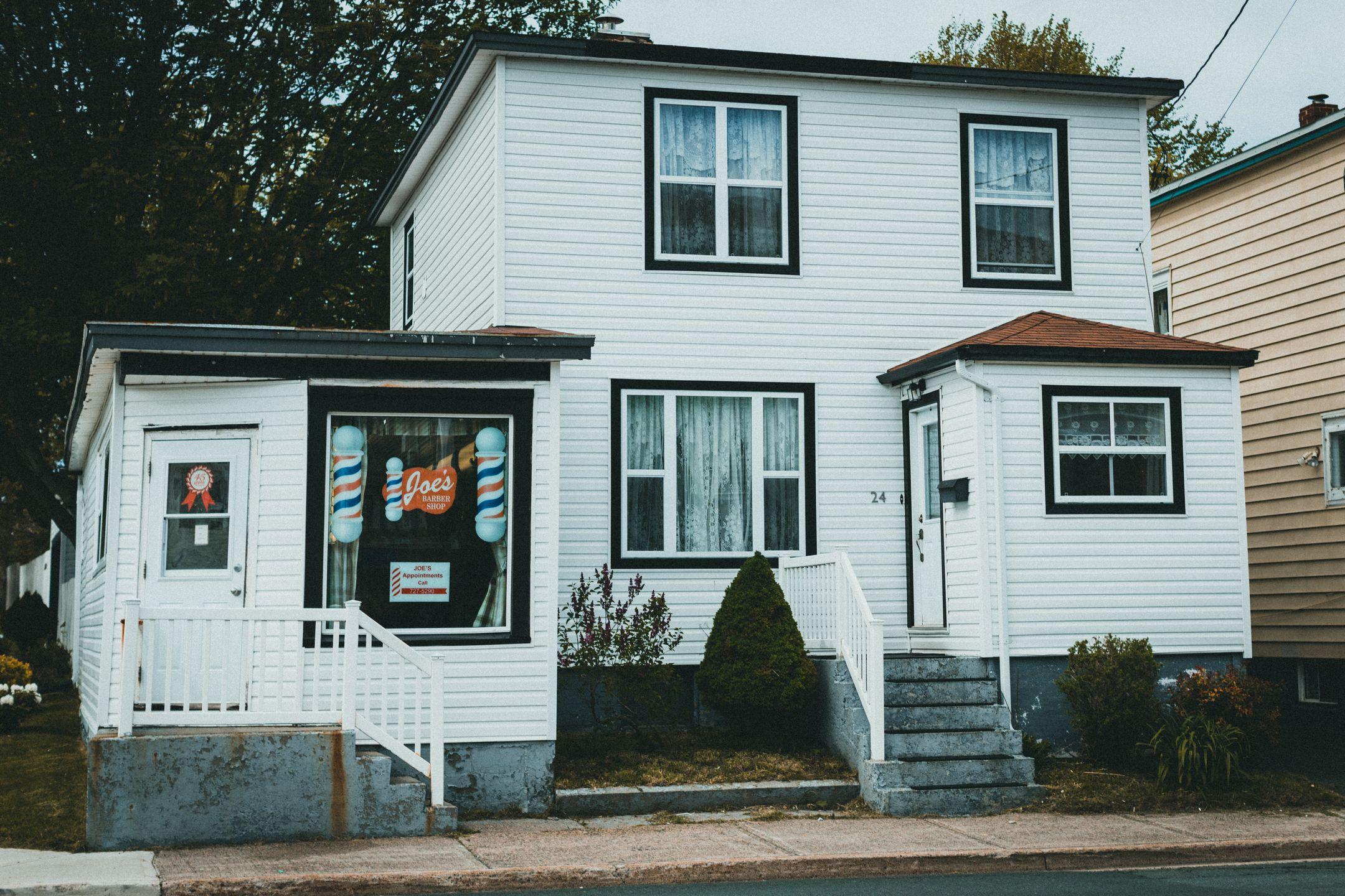 A quaint barbershop inside a white wooden house with a vintage exterior.