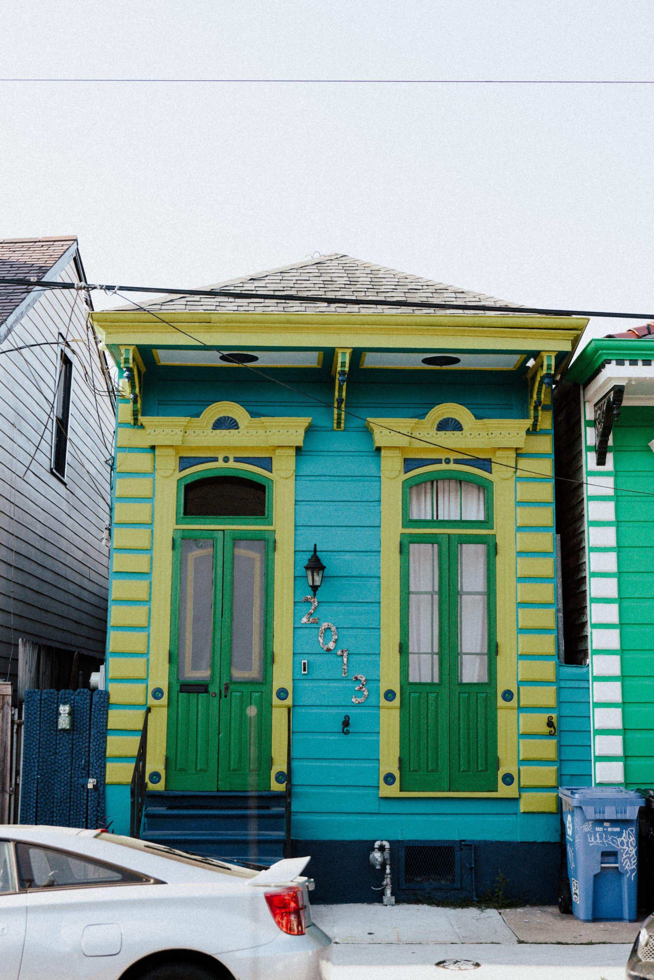 Vibrant blue and green New Orleans shotgun house style front with classic architectural details.