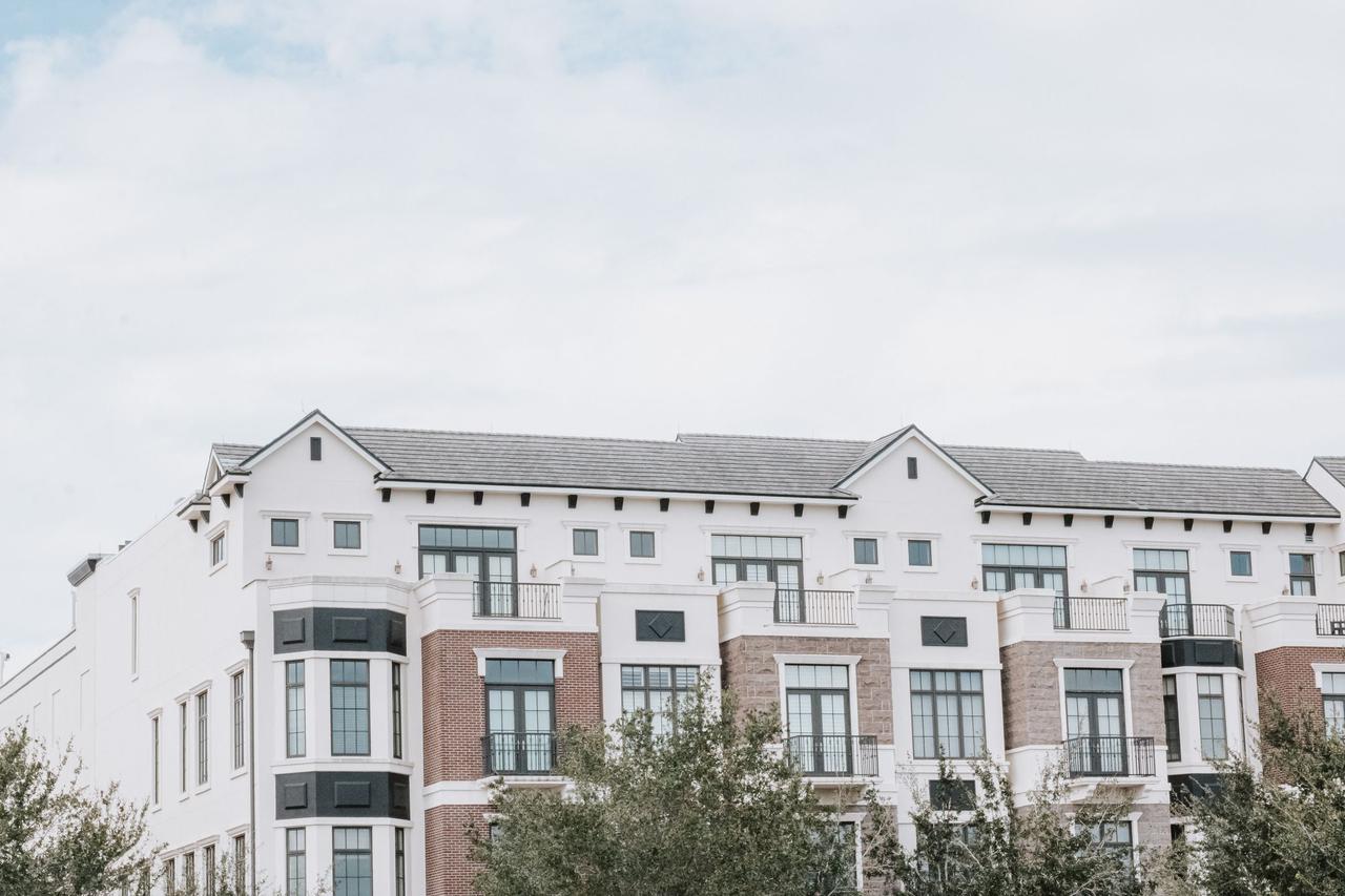A stylish, multi-story luxury apartment building with a contemporary facade against a clear sky.