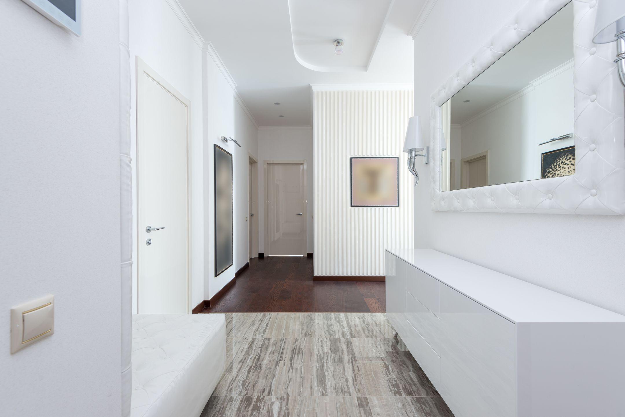 Bright corridor with contemporary design featuring white walls, minimal decor, and mirror.