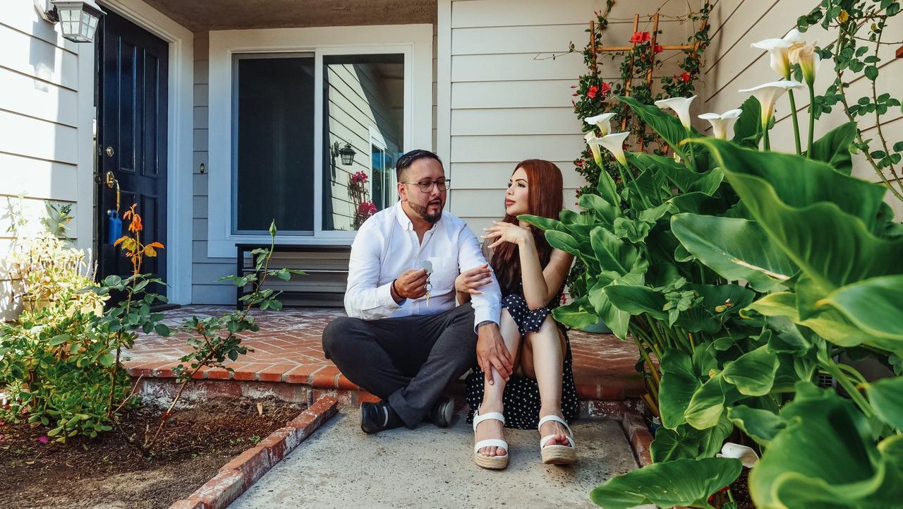 Happy couple enjoying time outside their new home surrounded by lush greenery.