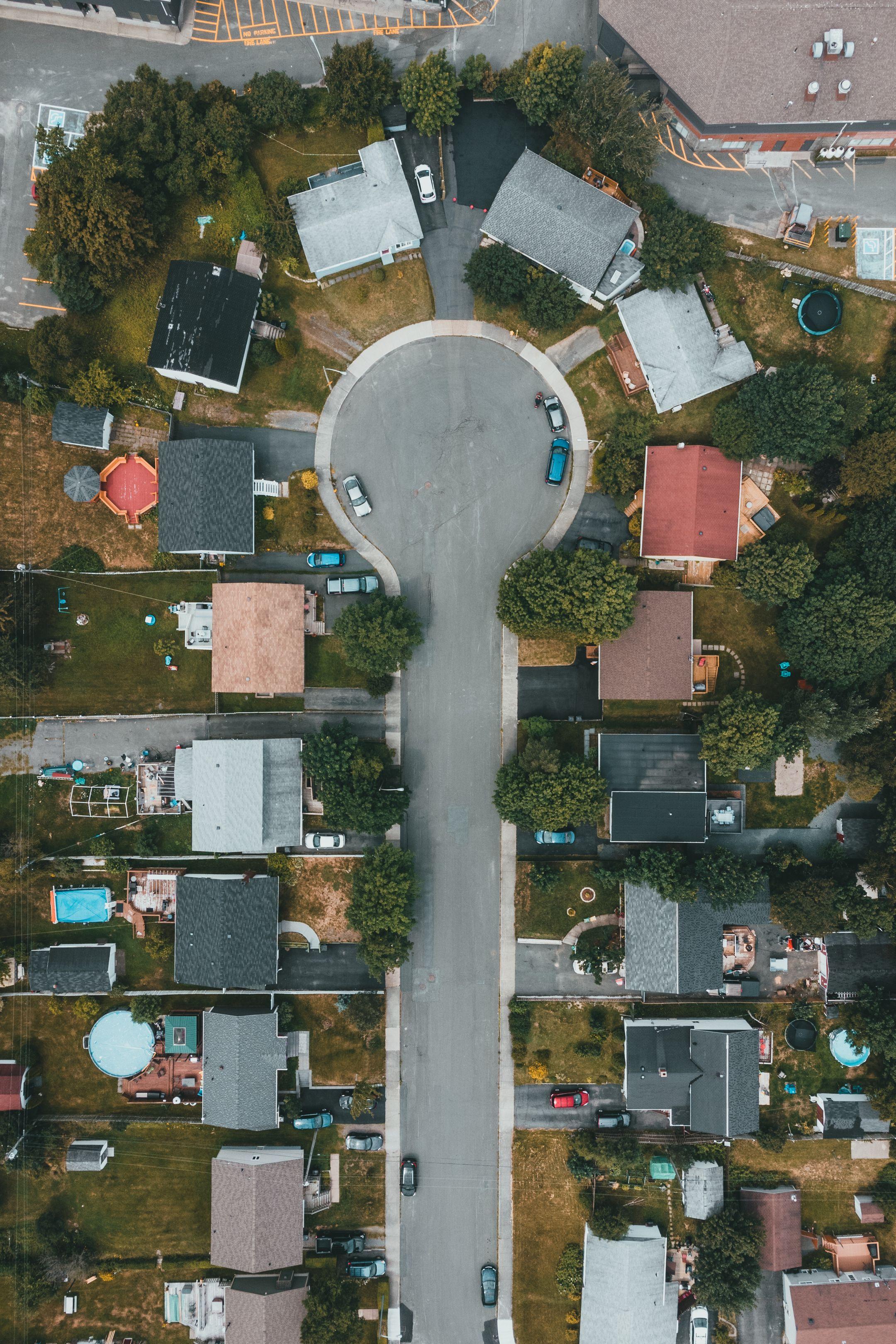 High angle aerial shot of a suburban cul-de-sac surrounded by houses, trees, and streets.