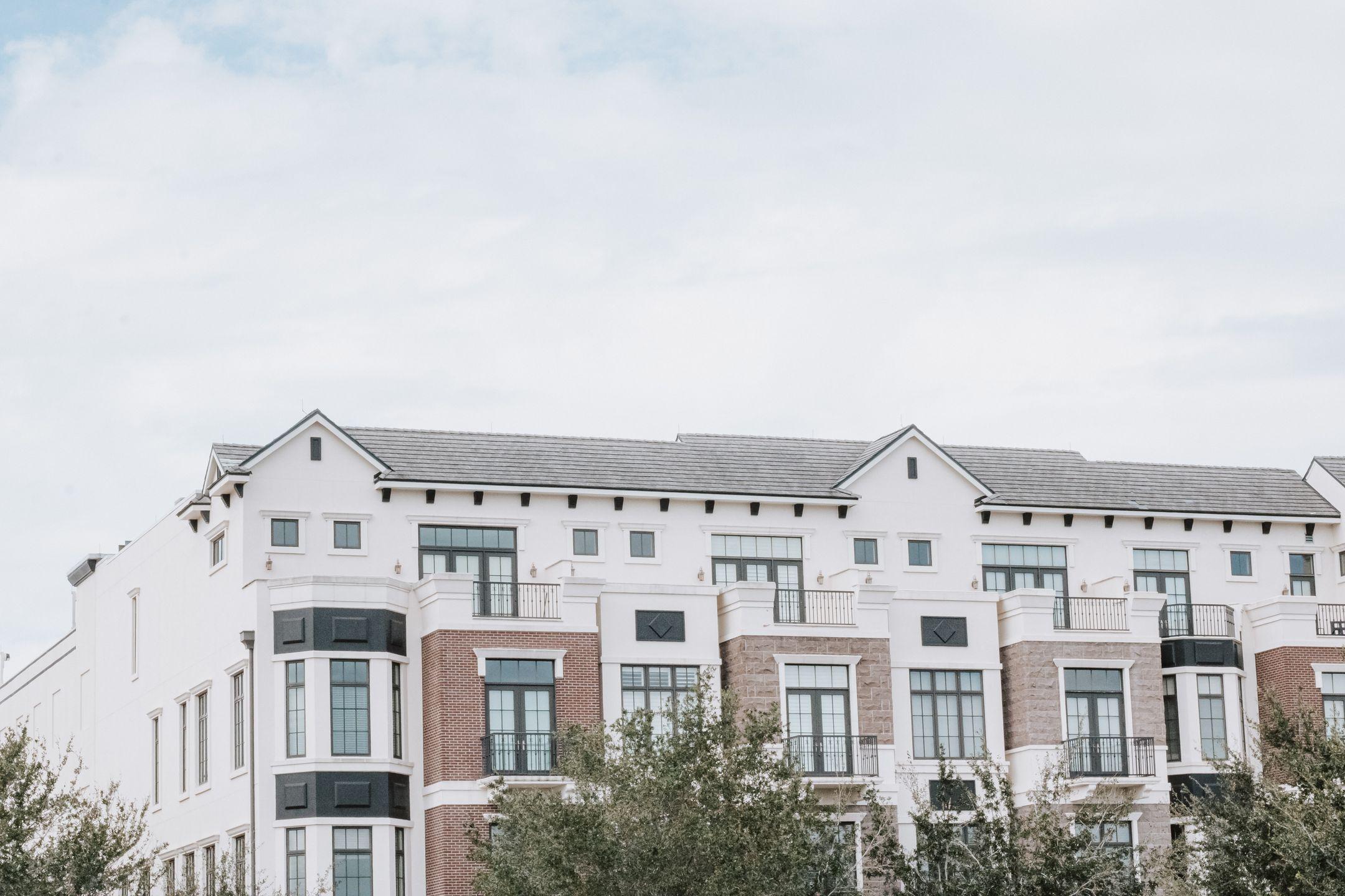 A stylish, multi-story luxury apartment building with a contemporary facade against a clear sky.