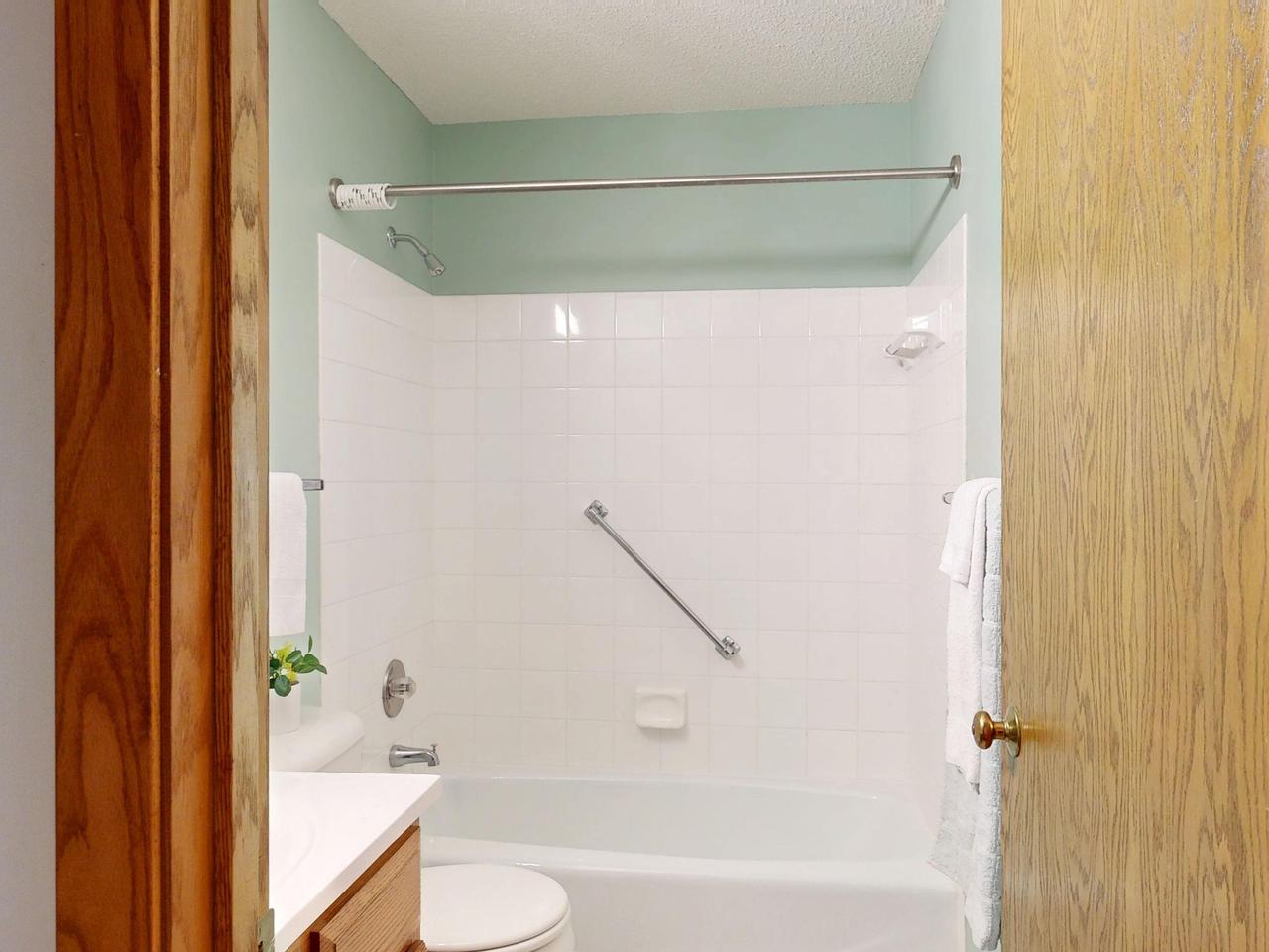 Clean and modern bathroom featuring white ceramic tiles and a bathtub.
