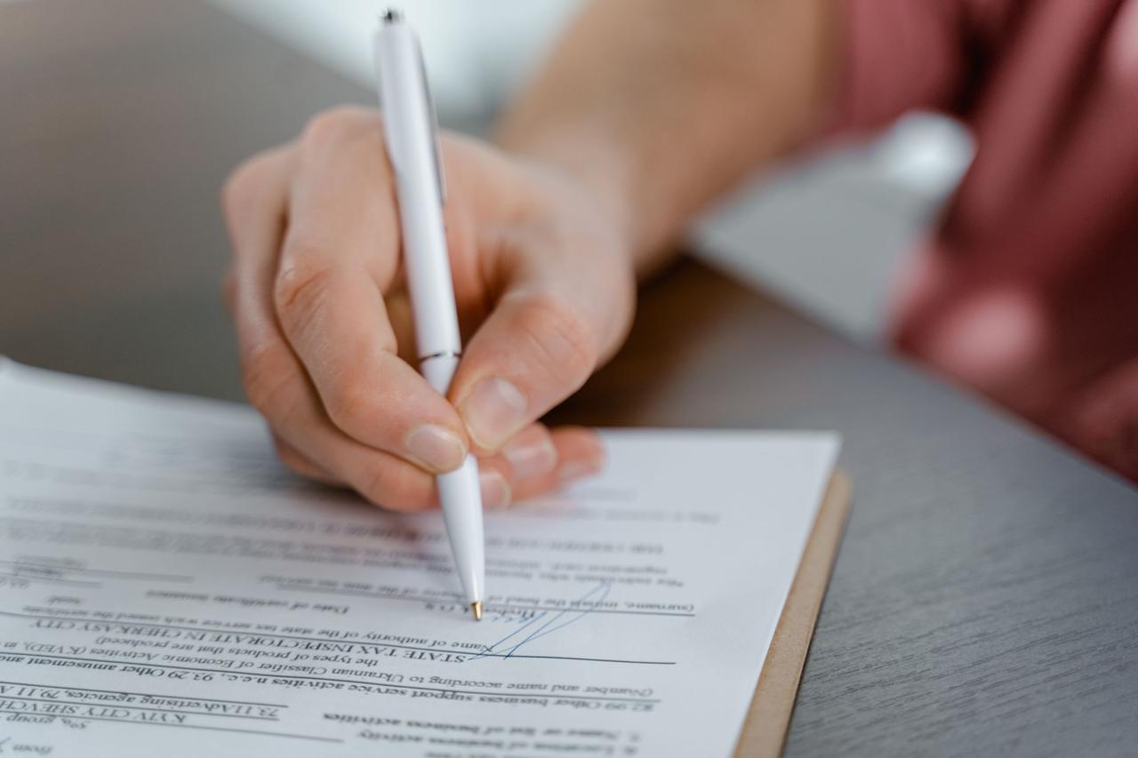 Hand signing a contract with a pen