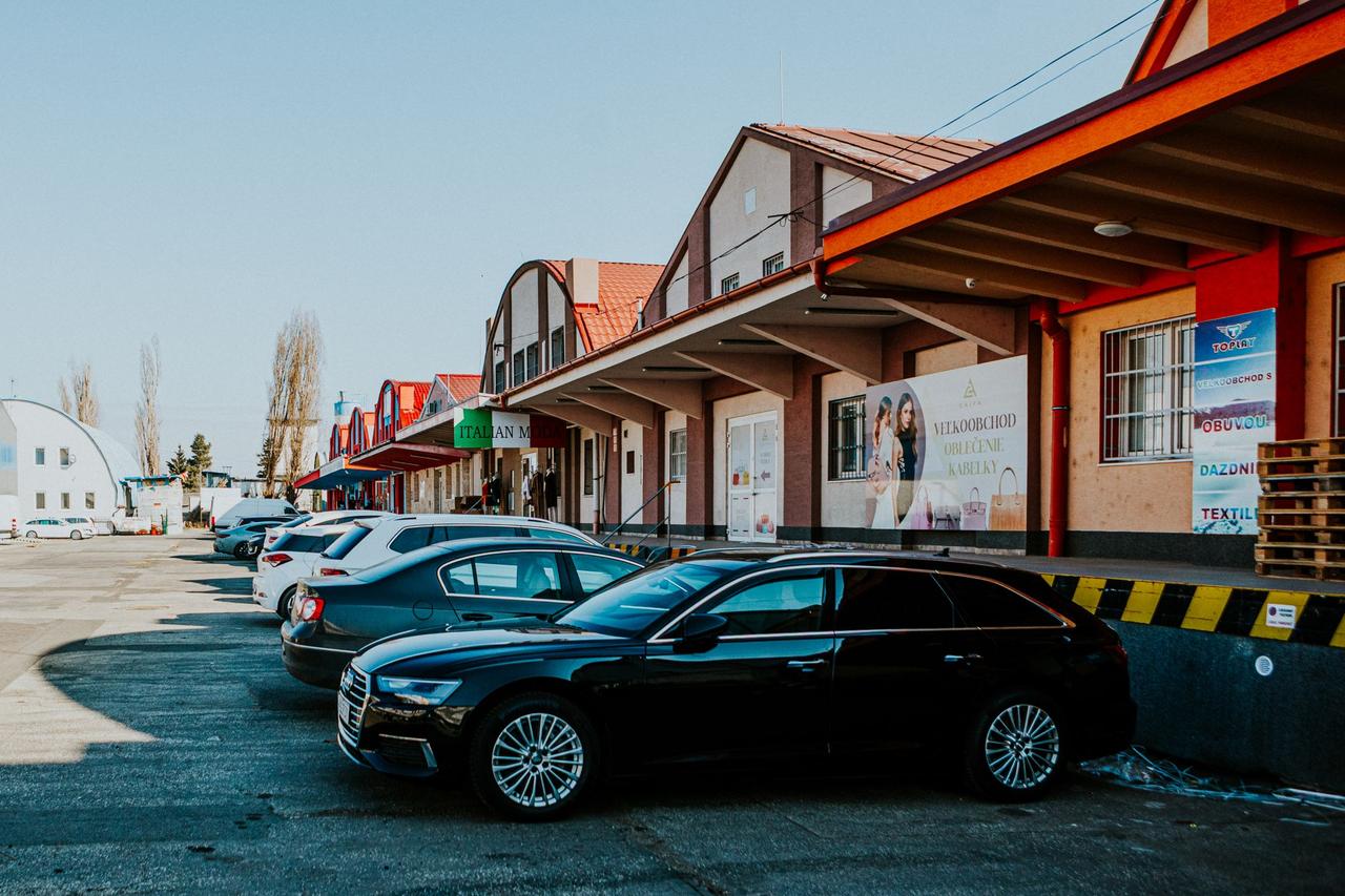 Parking lot with modern cars outside a commercial building with various shops.