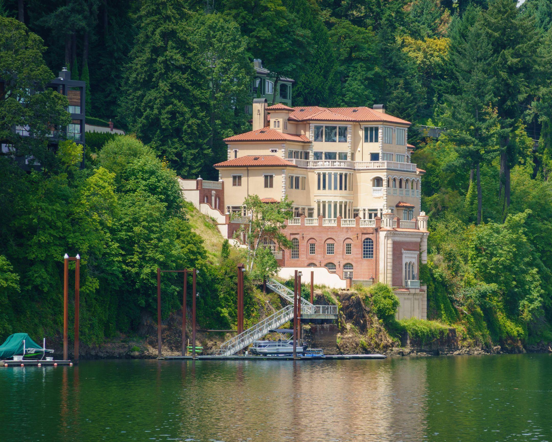 Charming lakeside villa with Mediterranean architecture set amidst vibrant green forests.