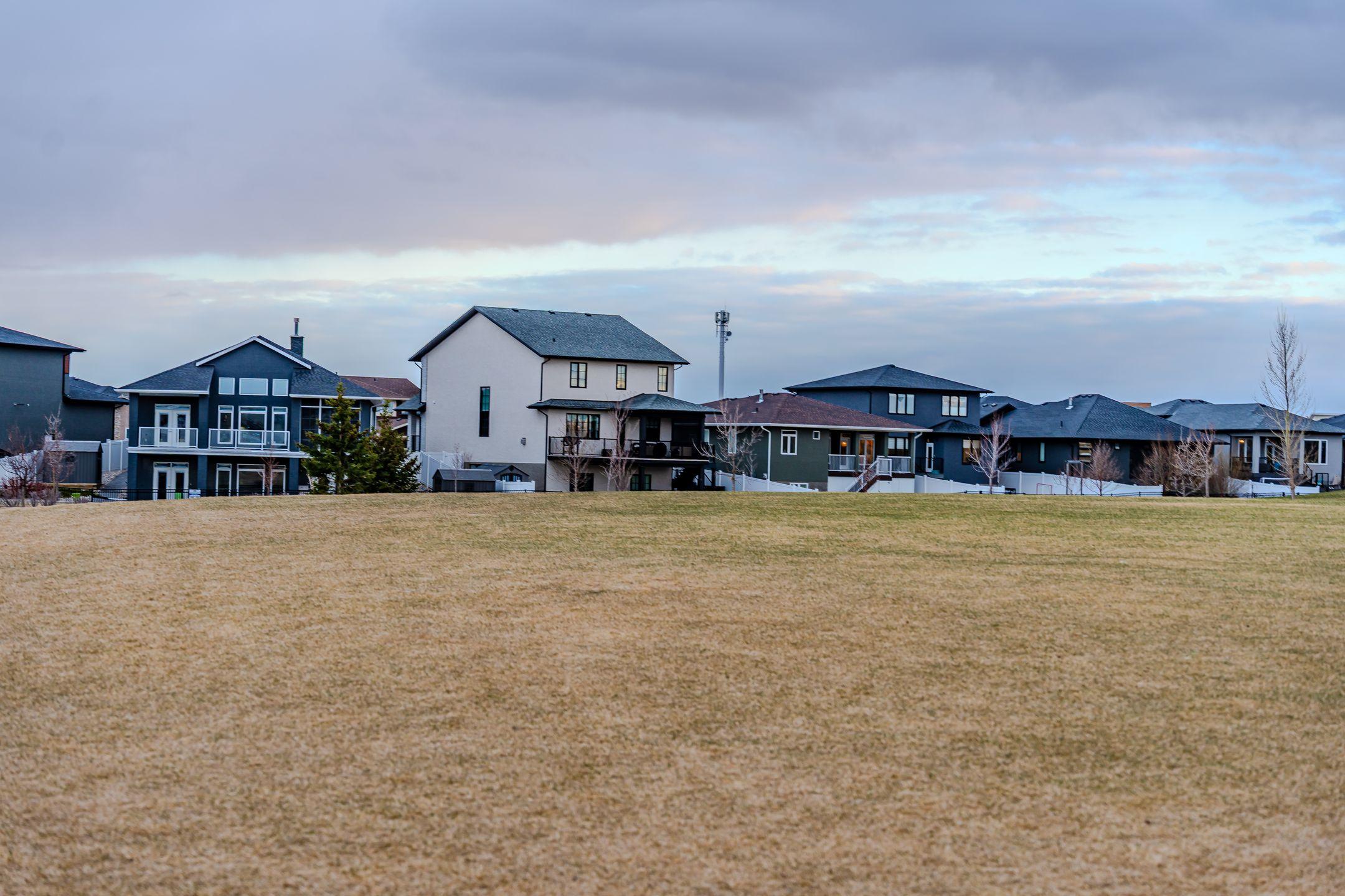 A view of suburban homes overlooking a vast open field under a partly cloudy sky.