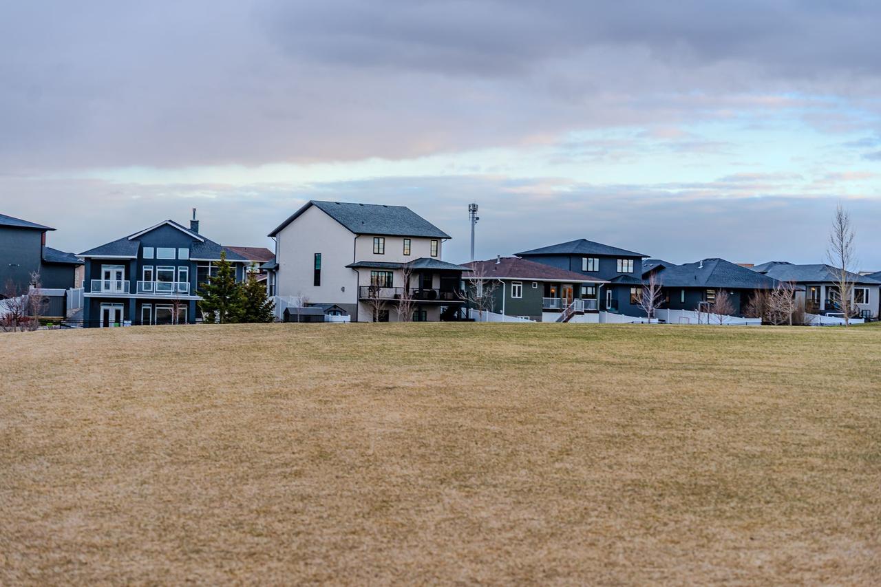 A view of suburban homes overlooking a vast open field under a partly cloudy sky.