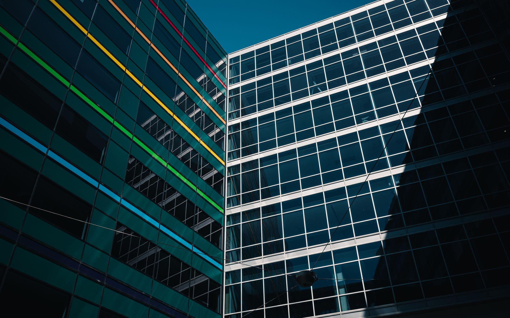 Architectural view of modern buildings with colorful stripes against a clear blue sky.