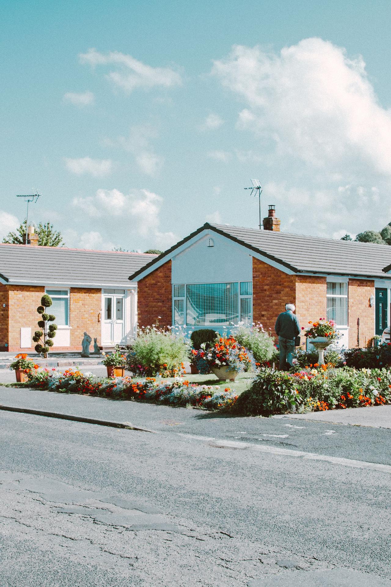 Beautiful suburban bungalow with a vibrant garden in full bloom on a sunny day.