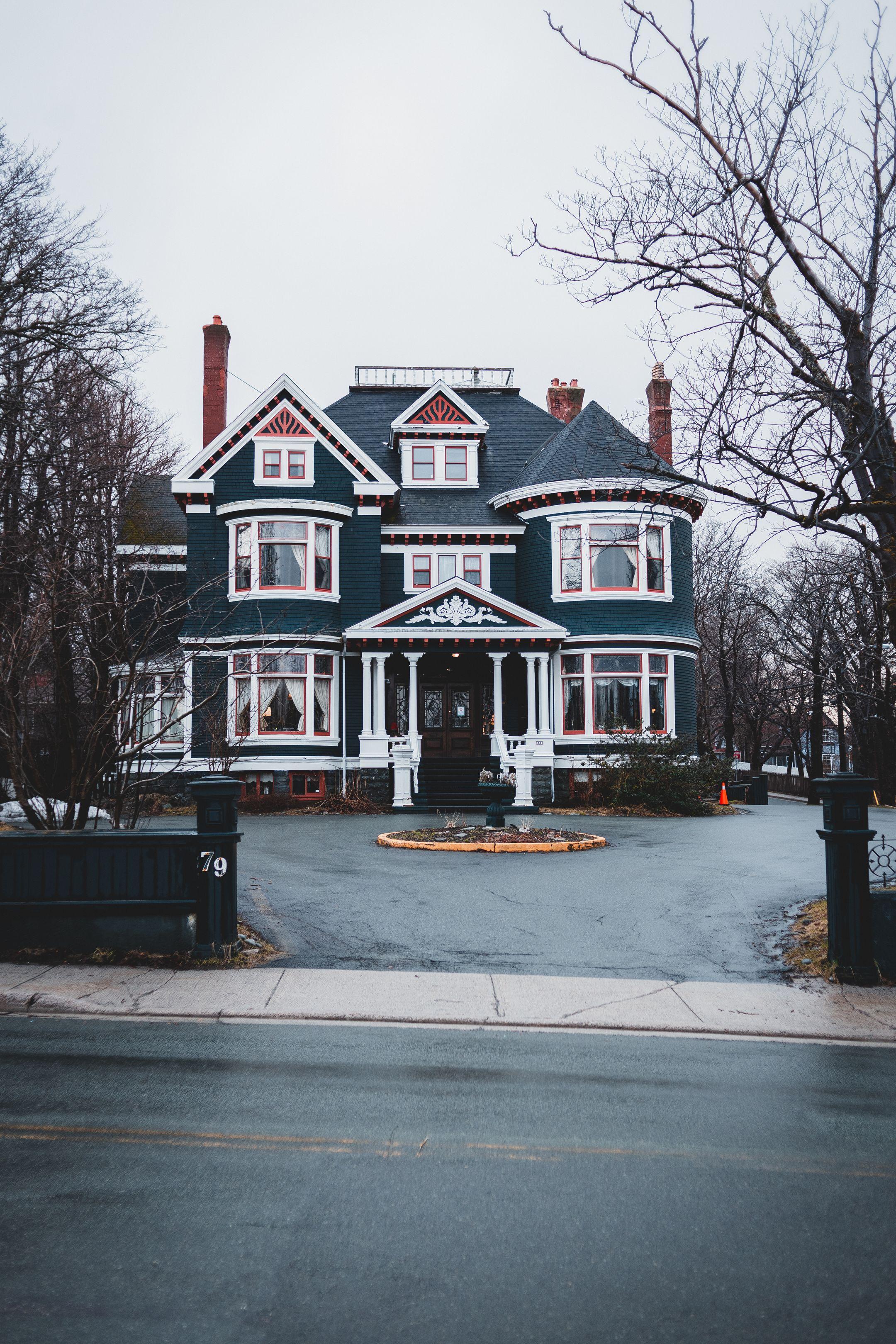 Exterior of modern dark blue multi storey cottage house with windows located near asphalt road in city on cloudy day