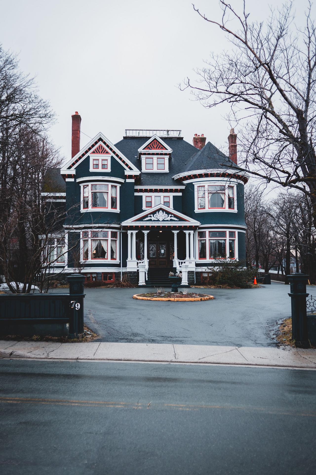 Exterior of modern dark blue multi storey cottage house with windows located near asphalt road in city on cloudy day