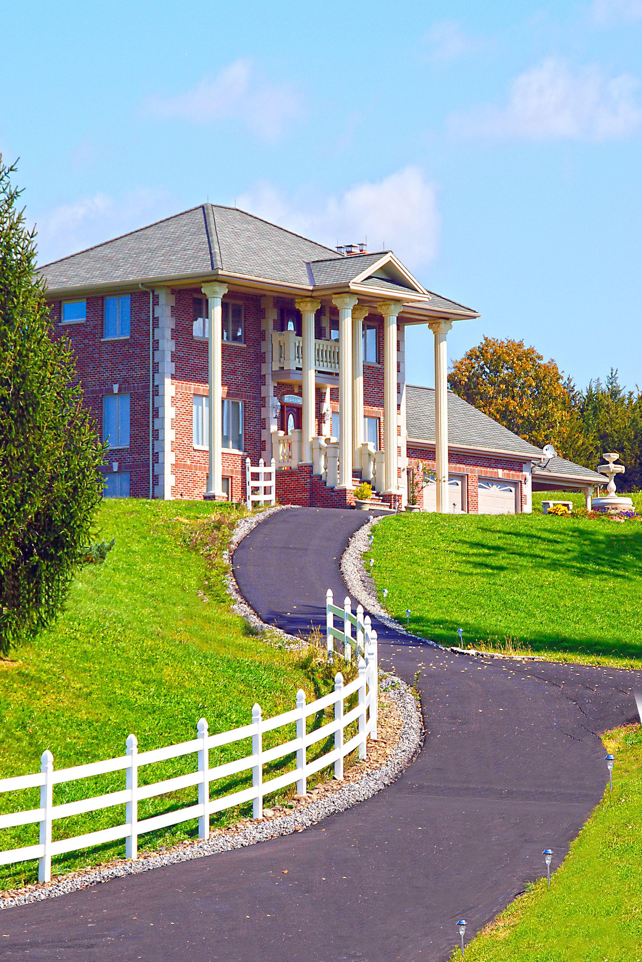 Stunning mansion with grand columns and a winding driveway in Greenville, NY.