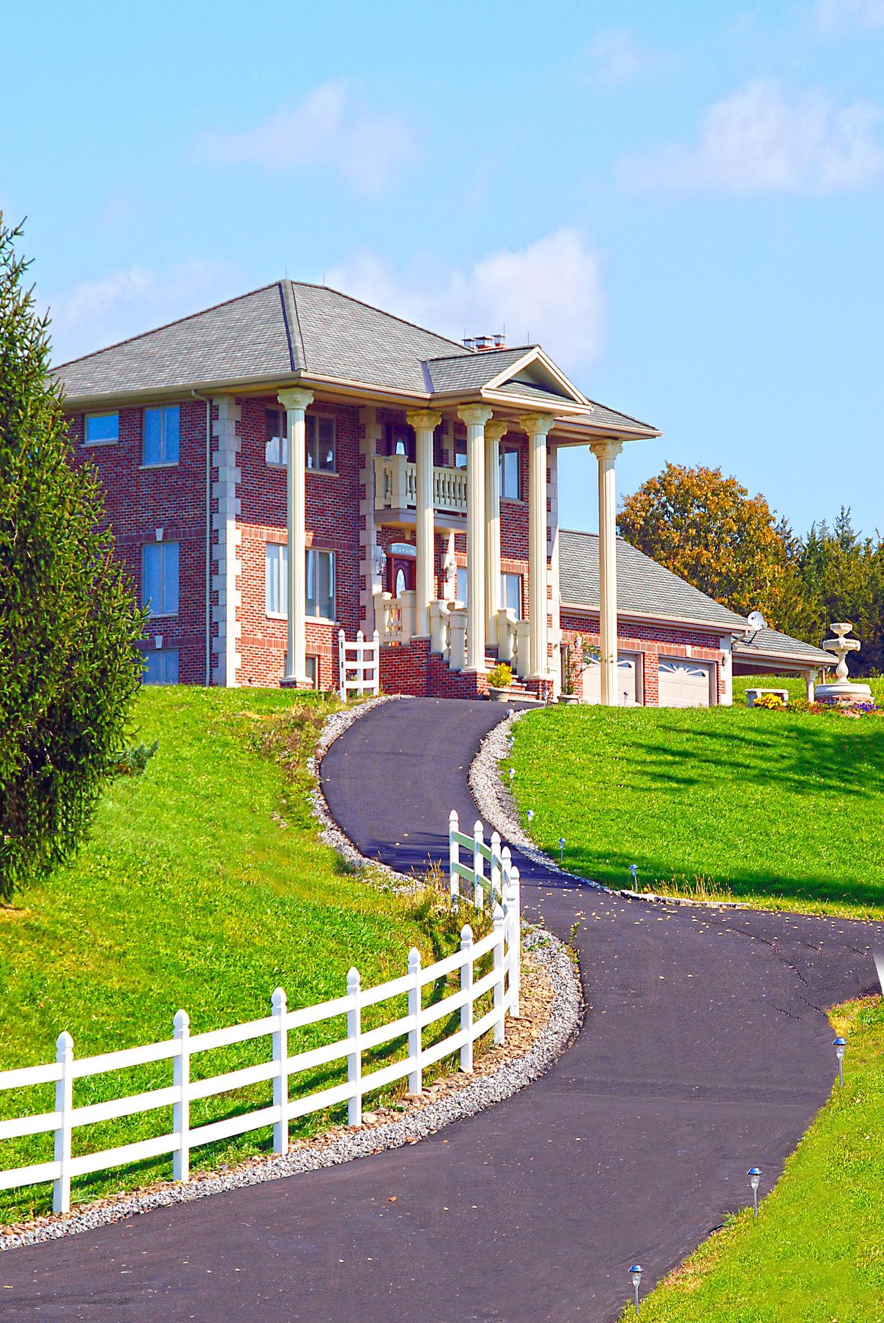 Stunning mansion with grand columns and a winding driveway in Greenville, NY.