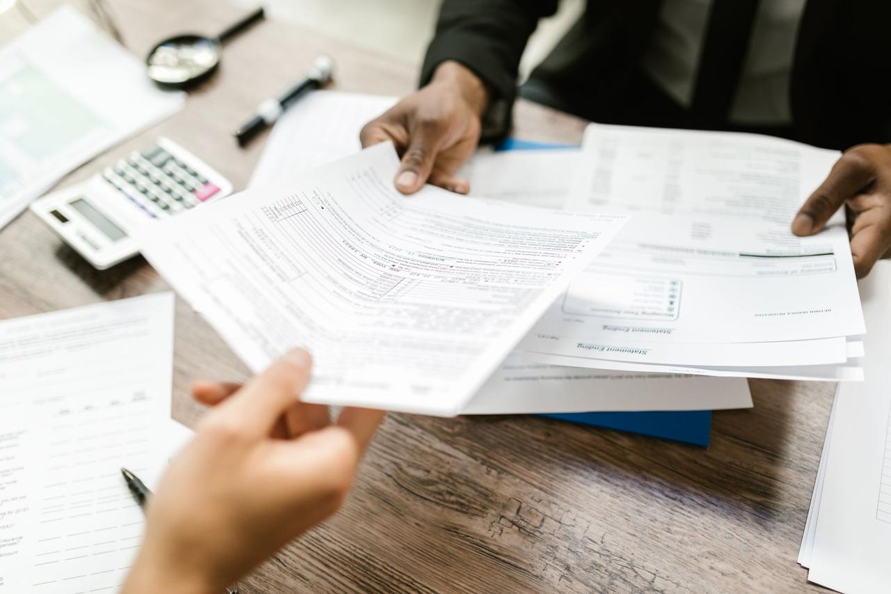 Hands comparing two sets of offer documents