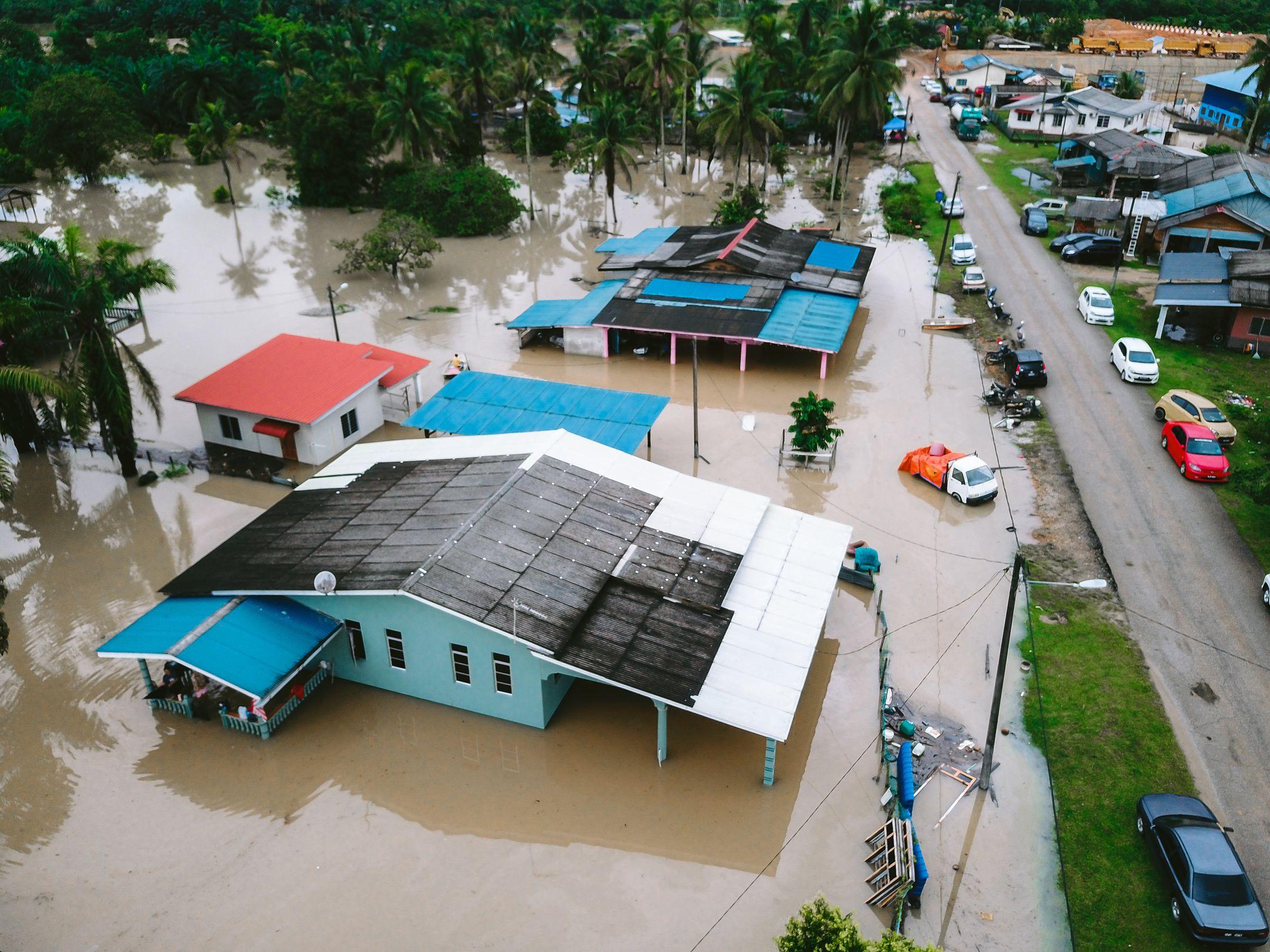 Aerial view of a flooded village in Kijal, Terengganu, Malaysia, showcasing submerged houses and streets.