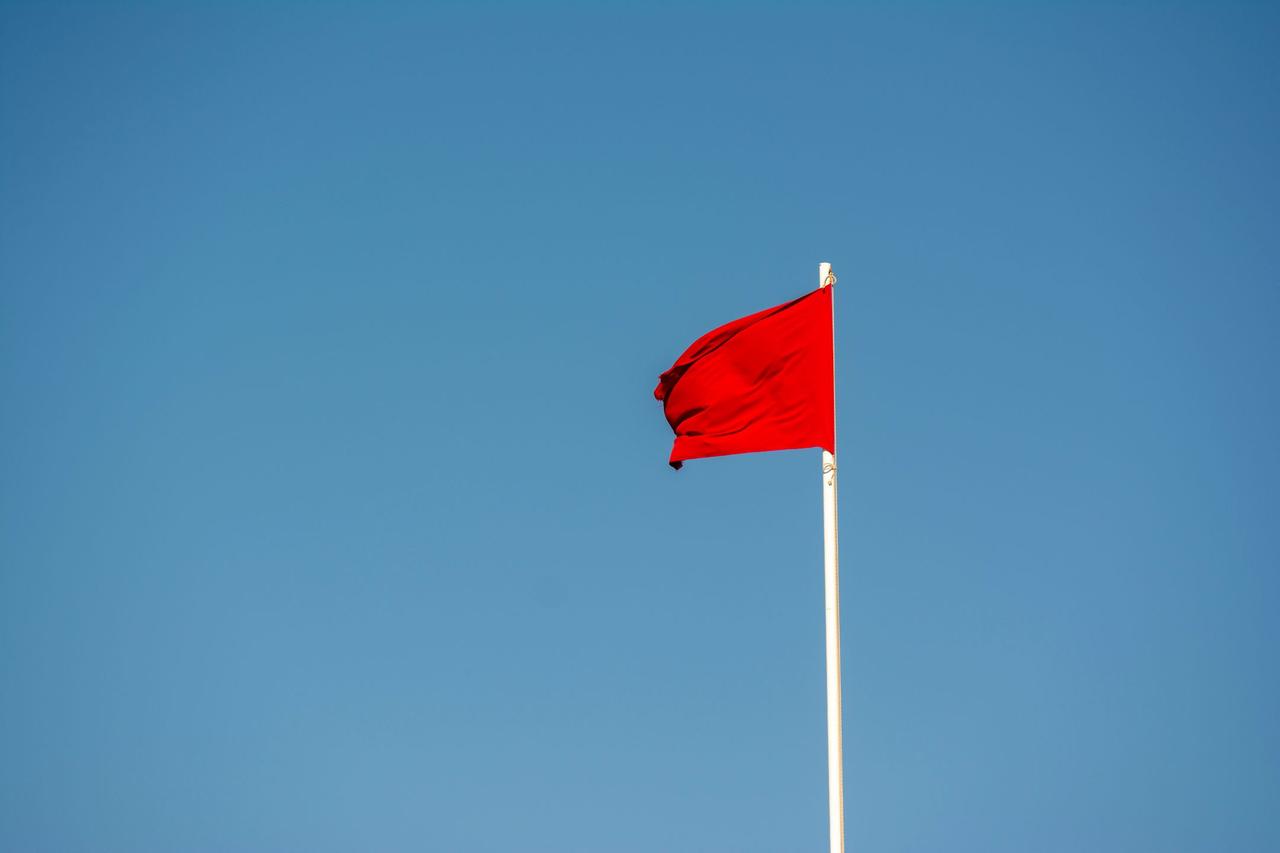 Red warning flag against a blue sky