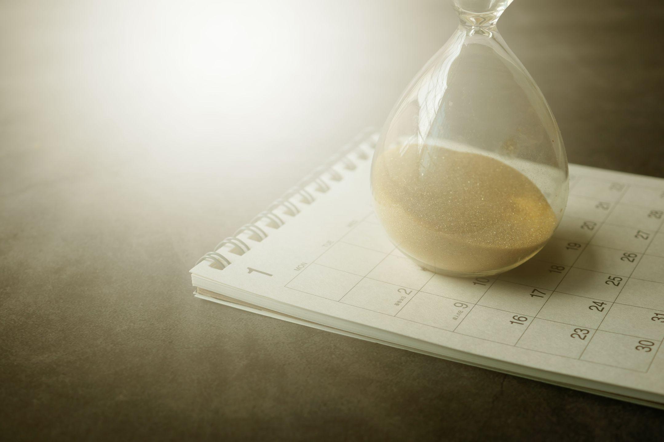An hourglass on a calendar captures the essence of time management and urgency.