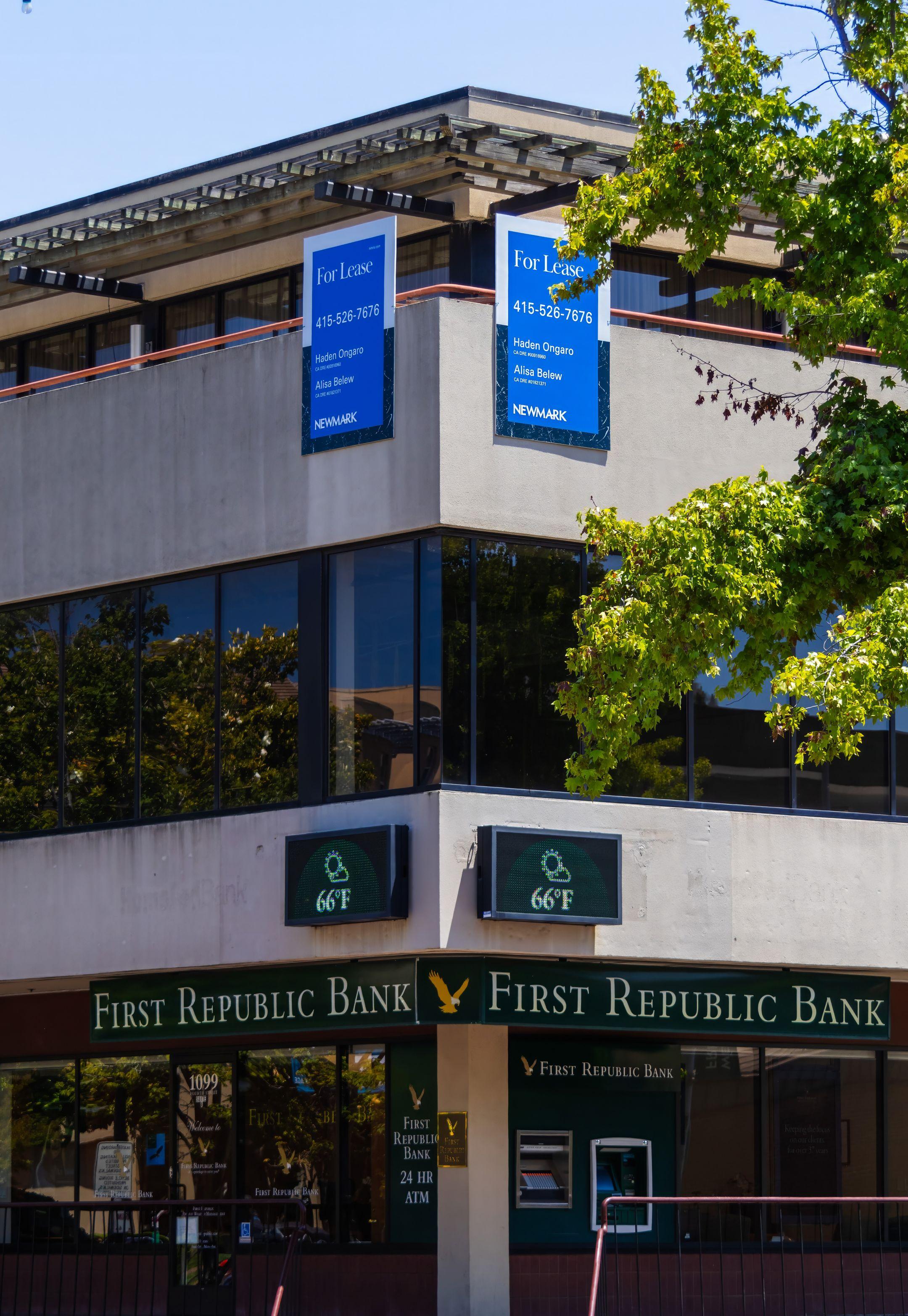 Exterior view of First Republic Bank with leasing signs and temperature display.