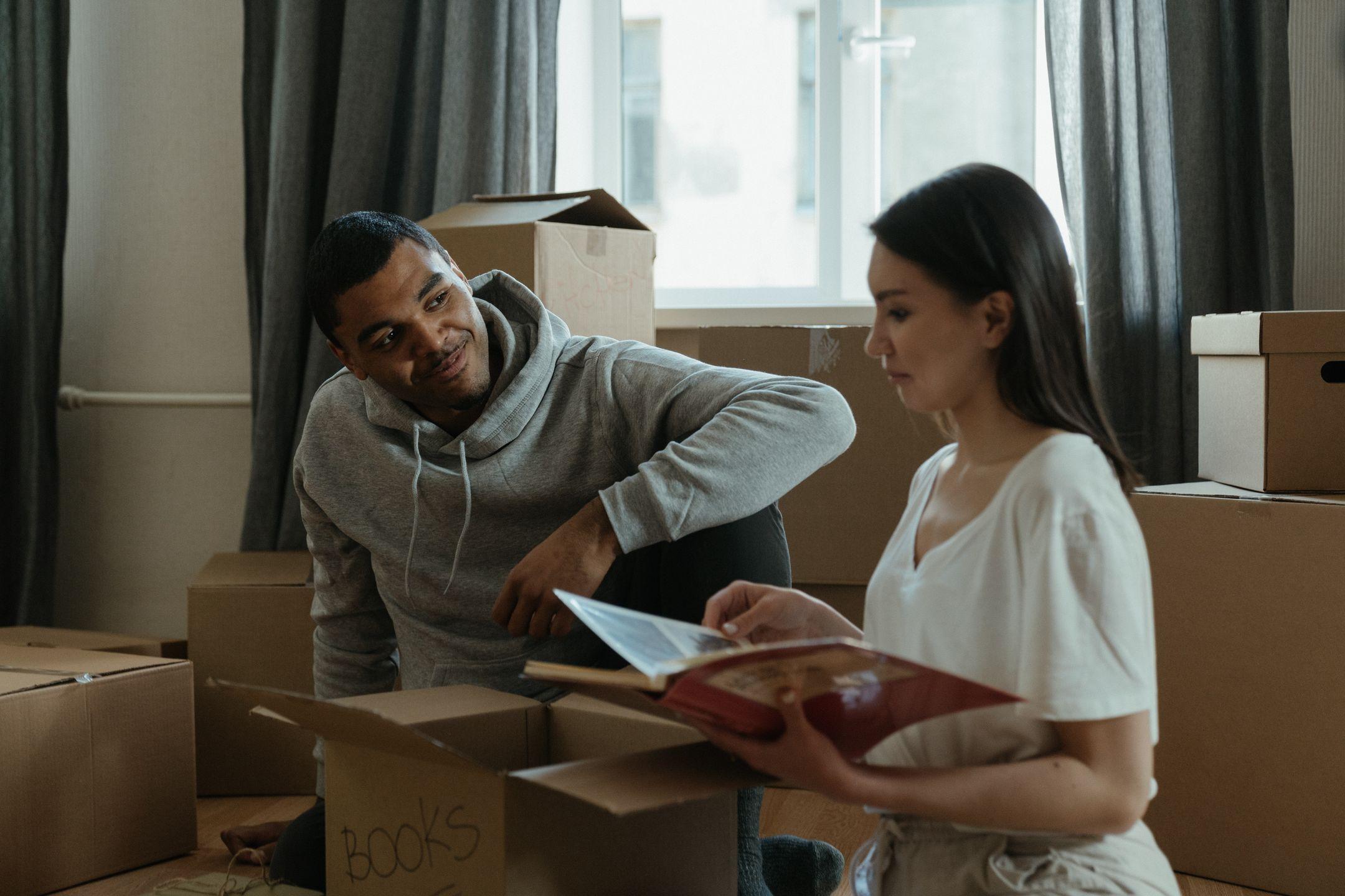 A couple exploring their new home while unpacking boxes and looking at a photo album.