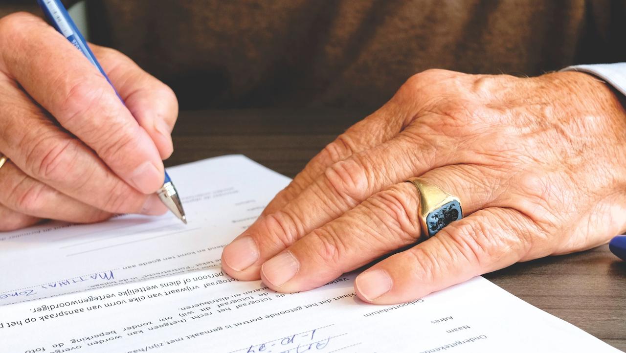 Older hands signing paperwork