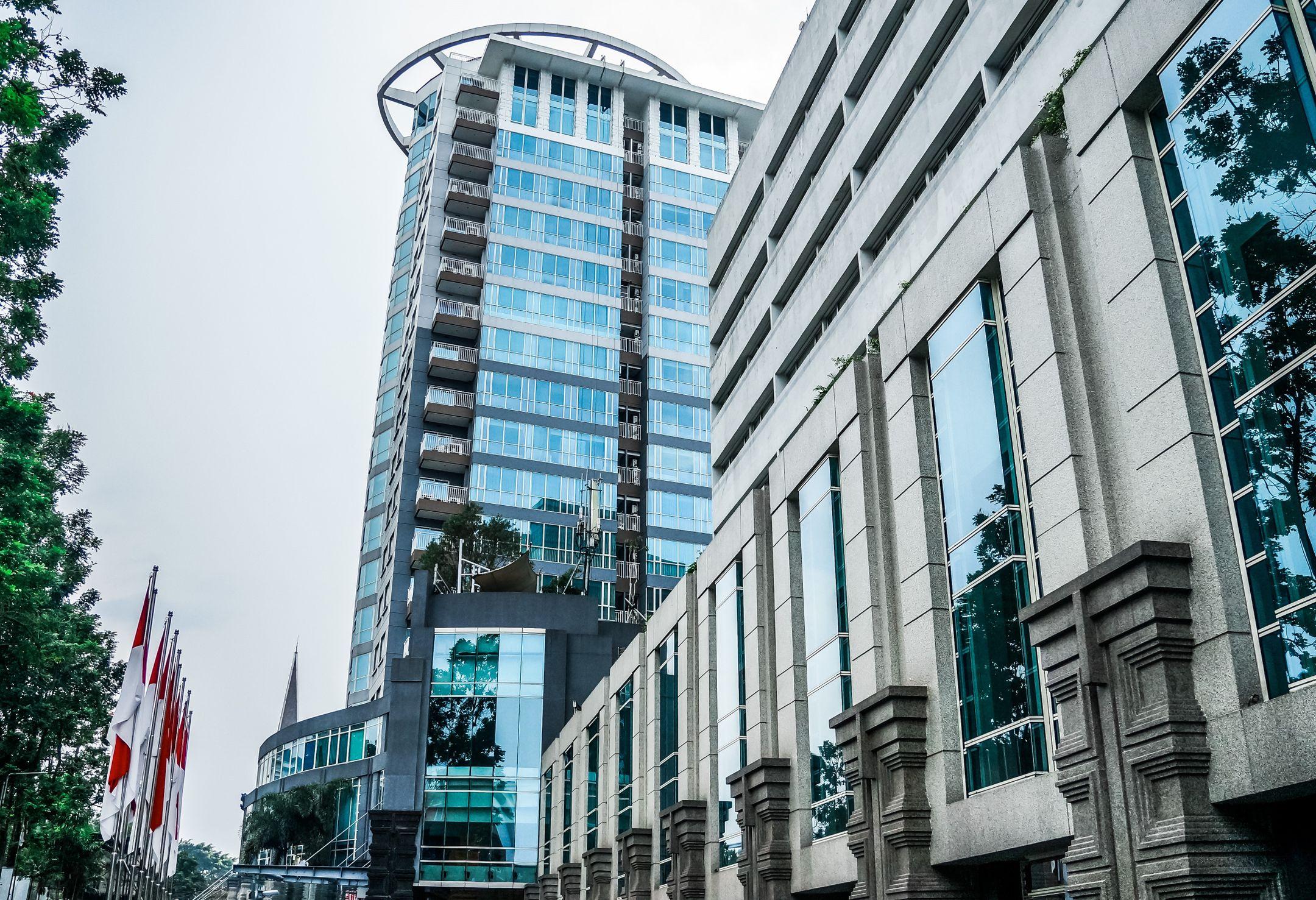 A contemporary skyscraper with flags in an urban area, showcasing modern architecture.
